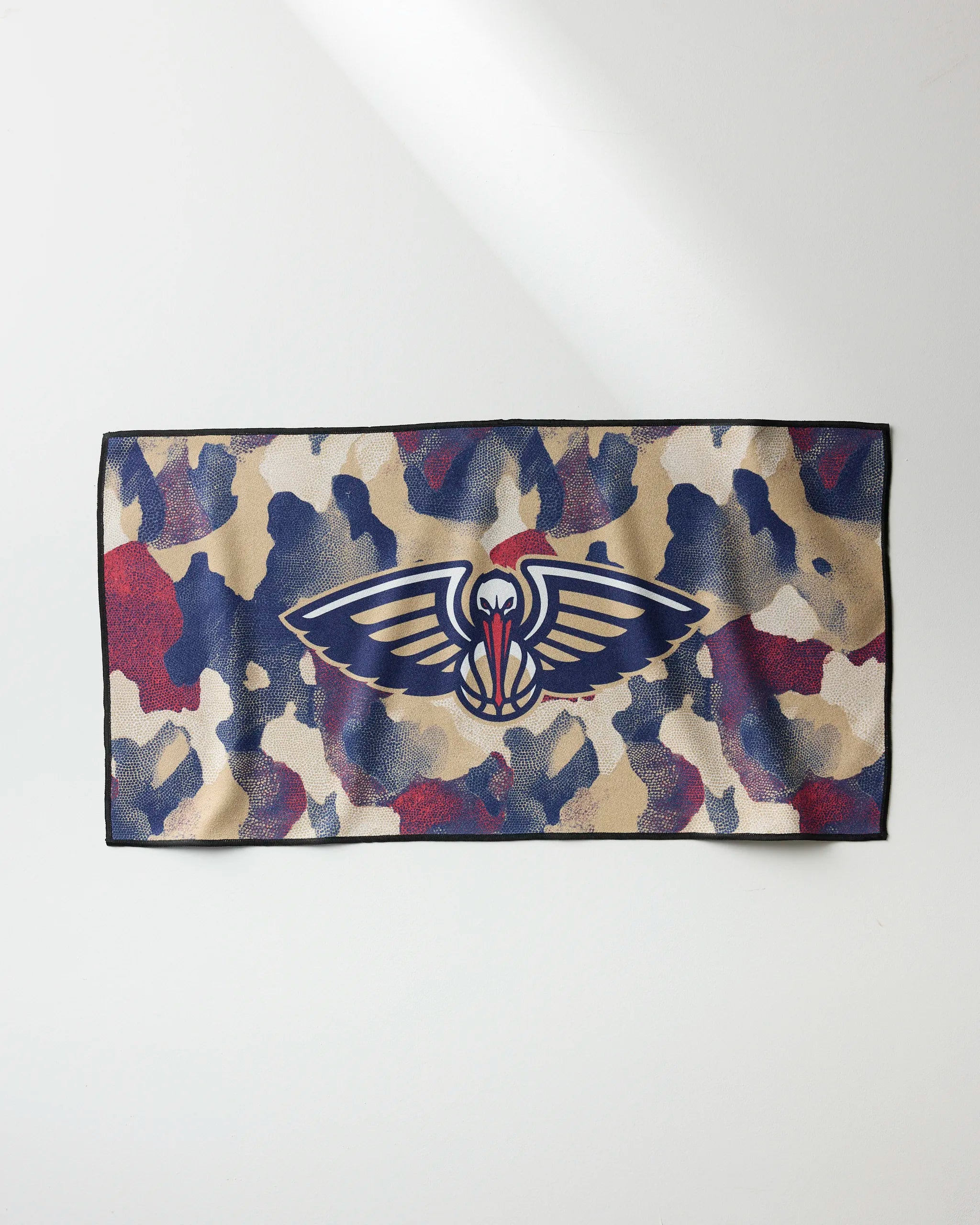 The NBALAB x Geometry Pelicans Camo fitness towel features a blue, beige, and red camo pattern with a large New Orleans Pelicans logo at the center. The quick-drying rectangular towel is displayed on a light background.