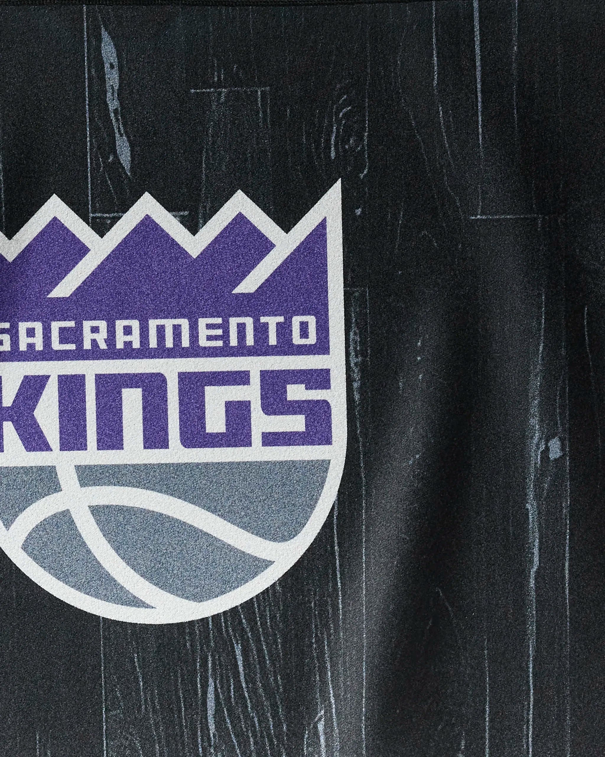 The image features the Sacramento Kings logo on a purple and gray shield, set against a dark textured backdrop—a stylish design for the "Kings Zone" NBA fitness towel by NBALAB x Geometry.