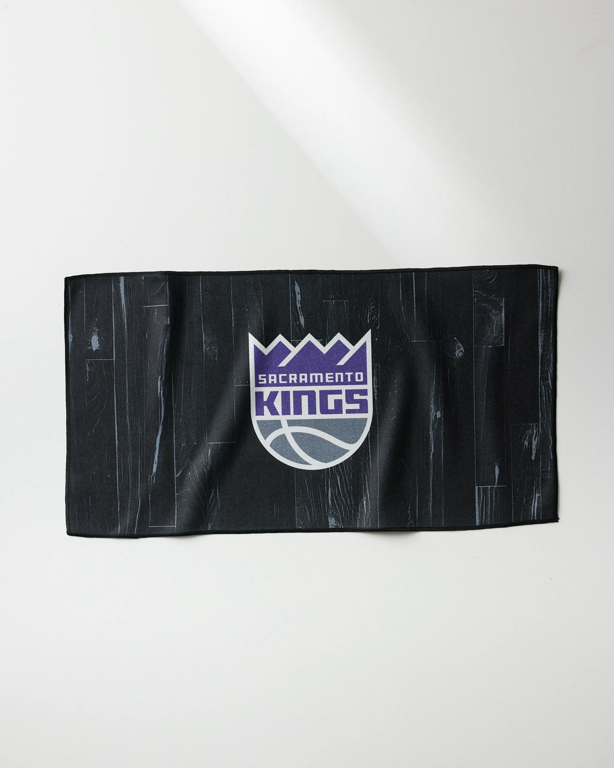 The Kings Zone by NBALAB x Geometry is a black quick-drying workout towel featuring the Sacramento Kings logo in purple, white, and gray, displayed on a white surface.