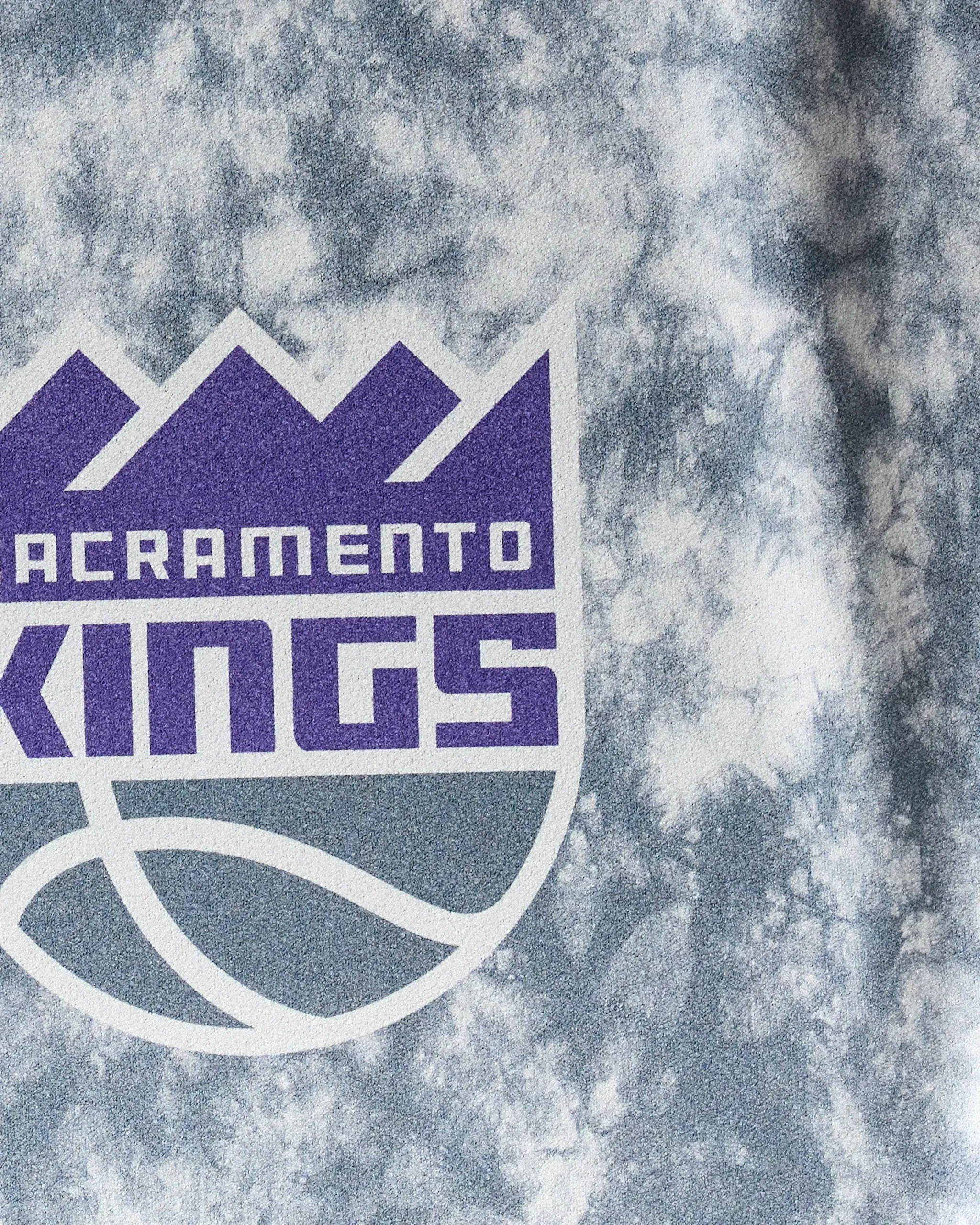 Close-up of the Sacramento Kings logo on the Kings Flash fitness towel by NBALAB x Geometry. This gray and white tie-dye NBA towel features a purple crown, stylized text, and basketball—ideal for fans who want style in their workout gear.