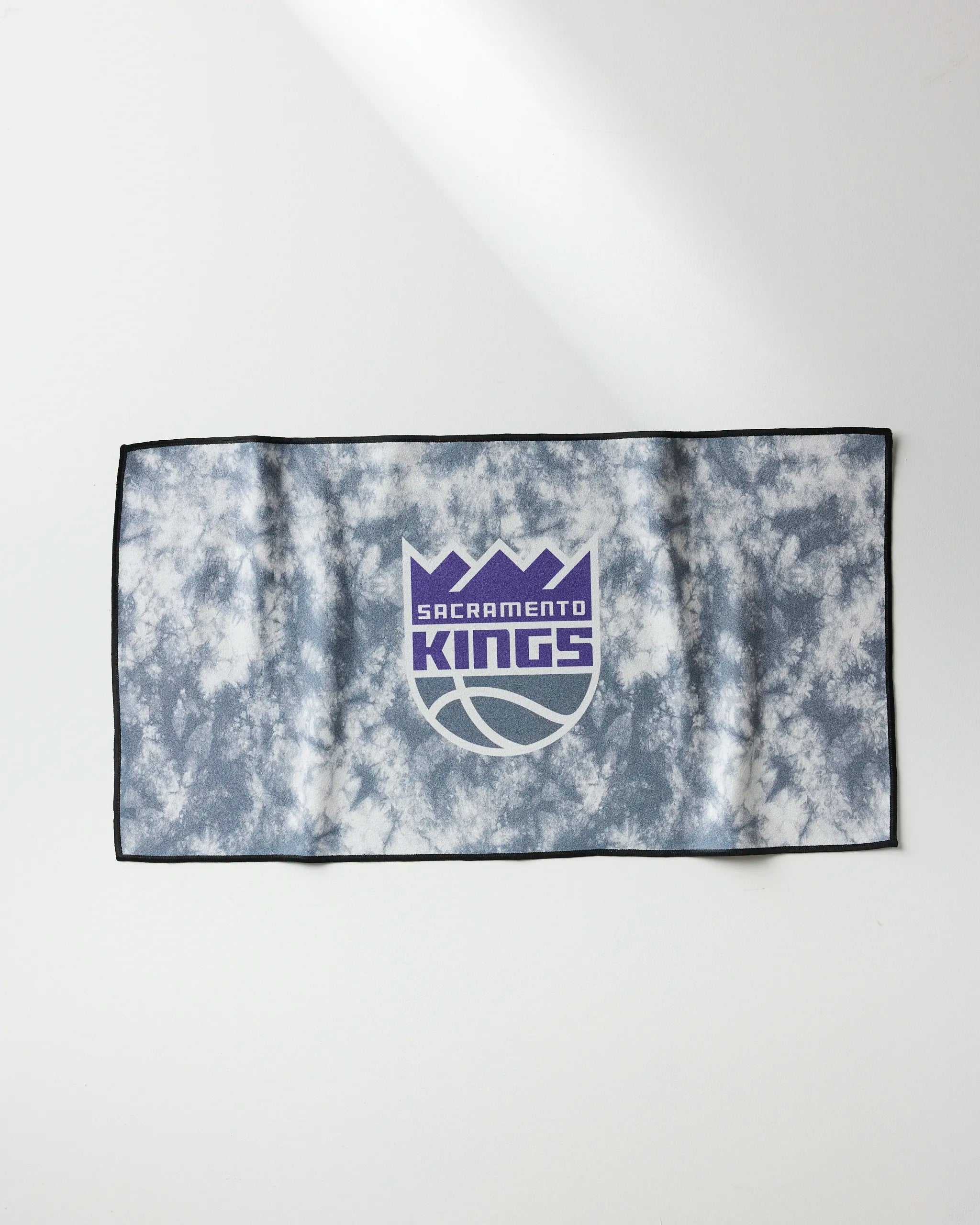 The Kings Flash towel by NBALAB x Geometry is a rectangular NBA fitness towel with a gray and white marble pattern, featuring the Sacramento Kings logo in purple and white at the center.