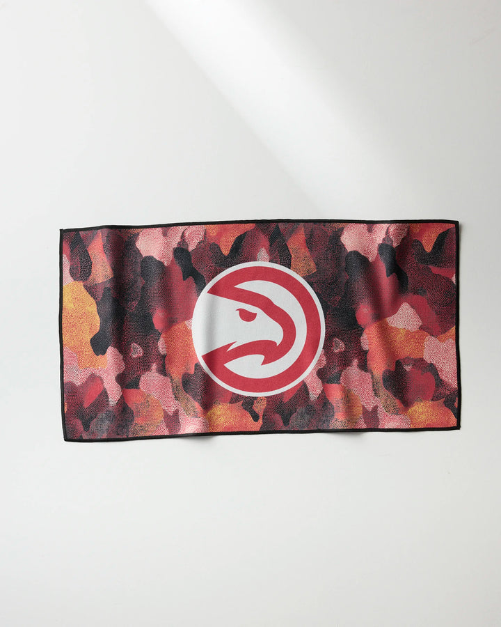 The Hawks Camo by NBALAB x Geometry is a rectangular, quick-drying workout towel with a red, pink, yellow, and black camo pattern featuring a white circle and red hawk head logo at the center.