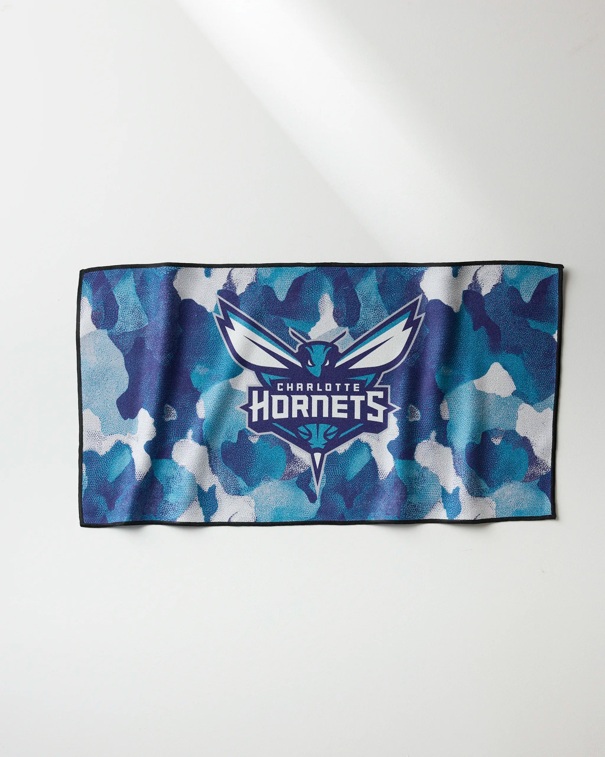The Hornets Camo towel by NBALAB x Geometry features a blue, teal, and white camouflage design with the Charlotte Hornets logo and name centered on a white background.