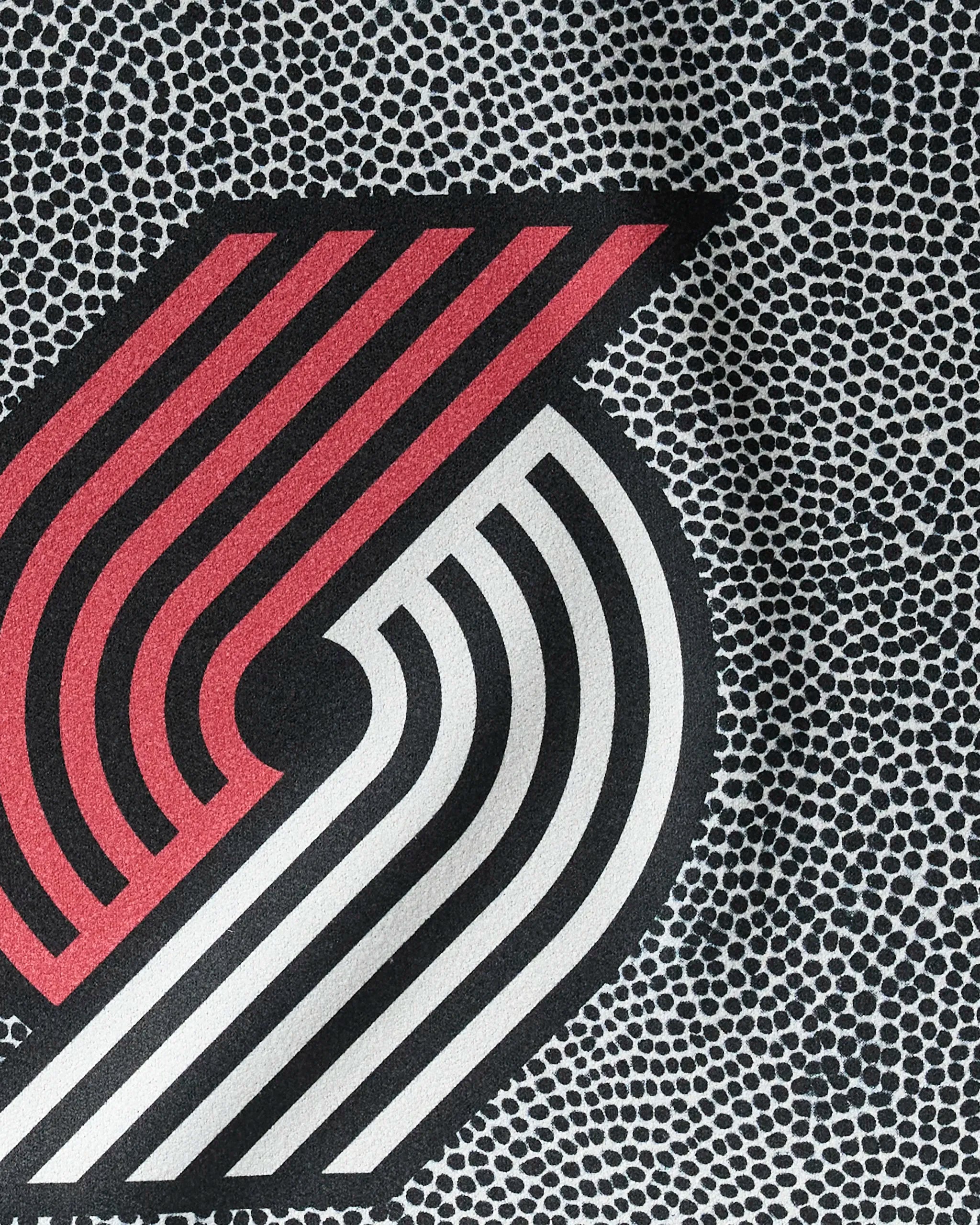 Close-up of the NBALAB x Geometry Trail Blazers Grip logo in red, black, and white with a dotted background—perfect inspiration for your NBA fitness or sustainable workout towel.