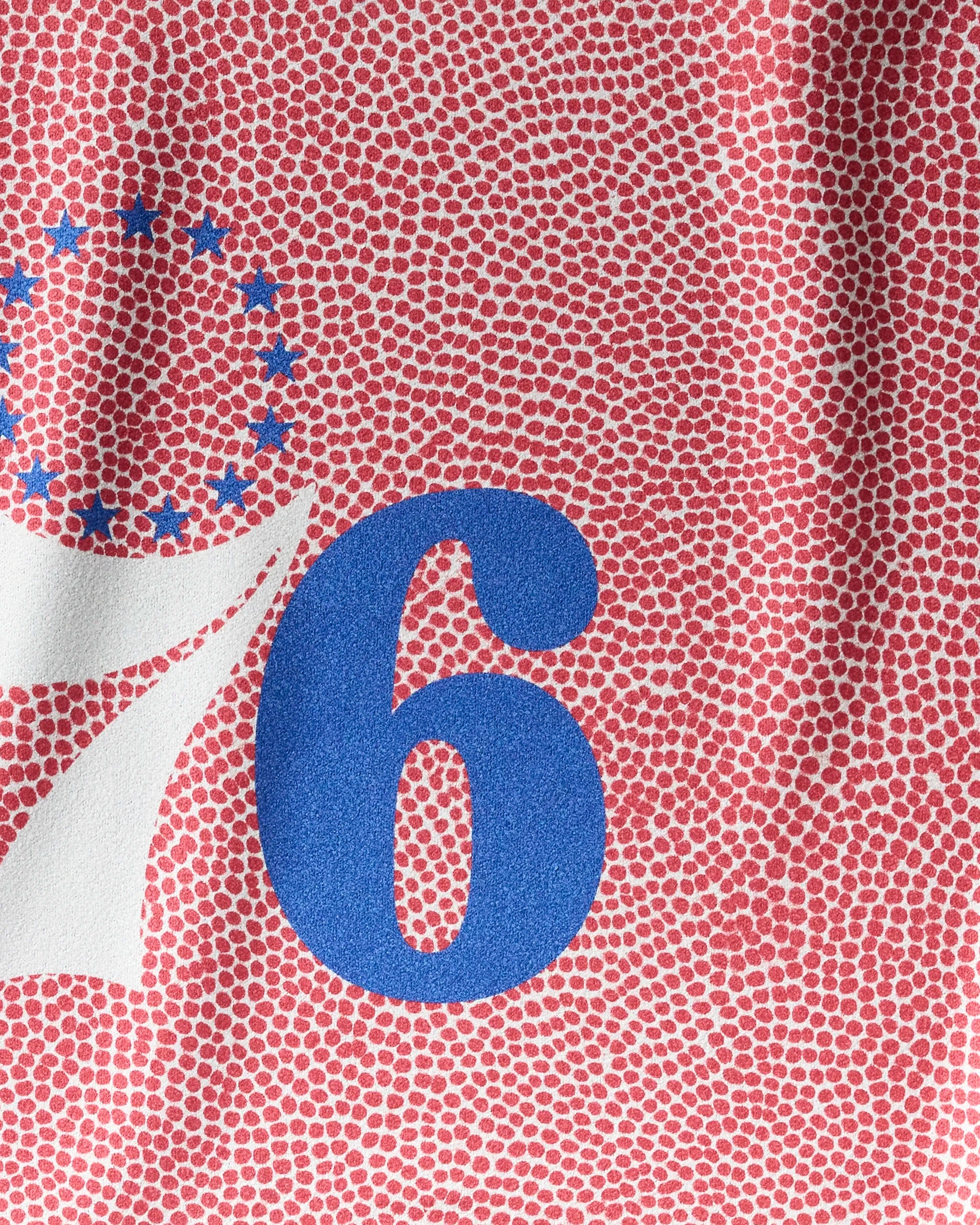 Close-up of the NBALAB x Geometry 76ers Grip gym towel’s textured red design, featuring a bold blue number 6, partial white 7, and blue stars—athletic inspiration from the Philadelphia 76ers logo in a quick-drying towel.