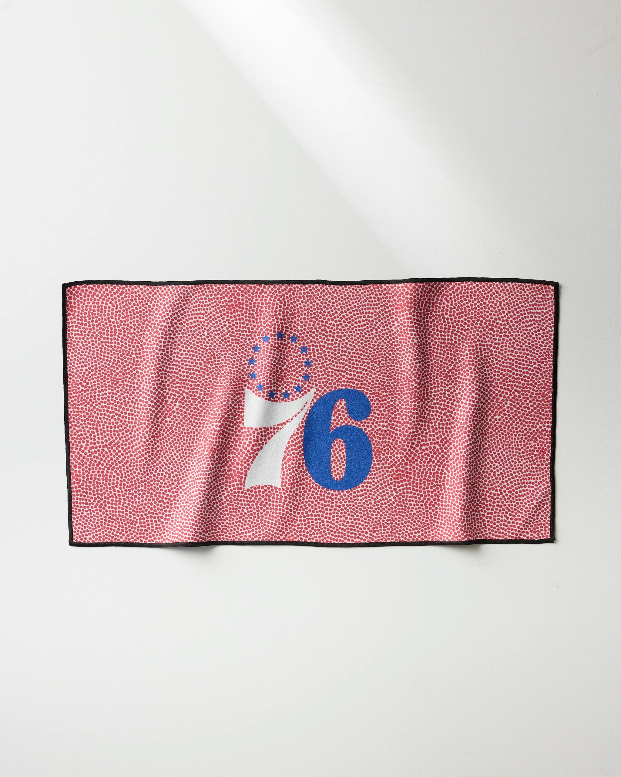 The 76ers Grip by NBALAB x Geometry is a rectangular NBA fitness towel with a red and white dotted design, featuring the number 76 in blue and white plus 13 blue stars above the 7—honoring the Philadelphia 76ers basketball team.