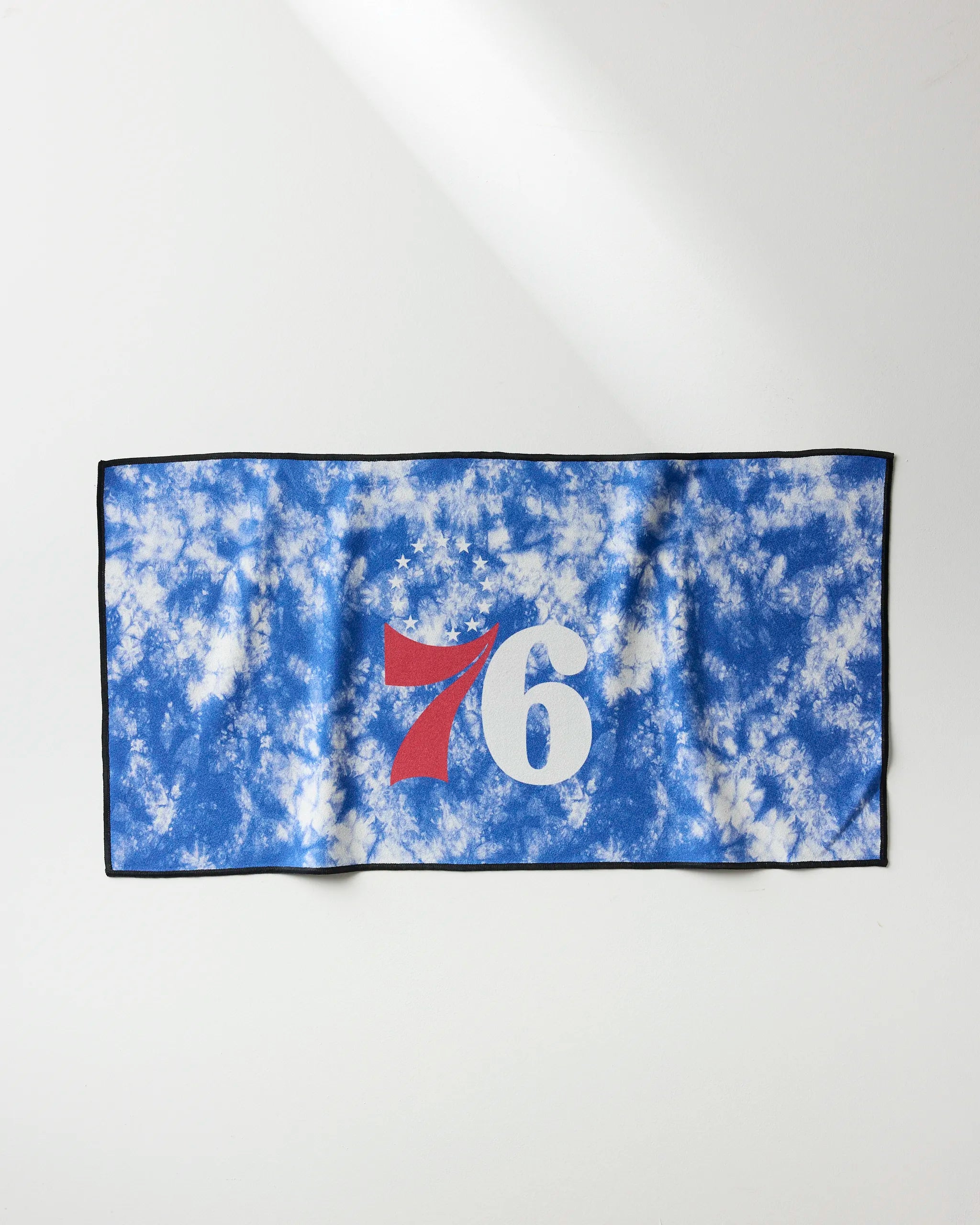 The NBALAB x Geometry 76ers Flash is a blue and white tie-dye quick-drying gym towel featuring a large red and white "76" at the center, shown laid flat on a white surface.