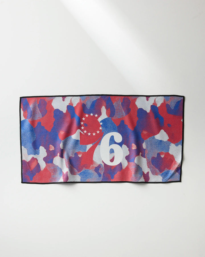 The NBALAB x Geometry 76ers Camo fitness towel features a red, blue, and white camouflage design with a white number 6 and partial circle of stars on the left side. It's rectangular and quick-drying for intense gym sessions.