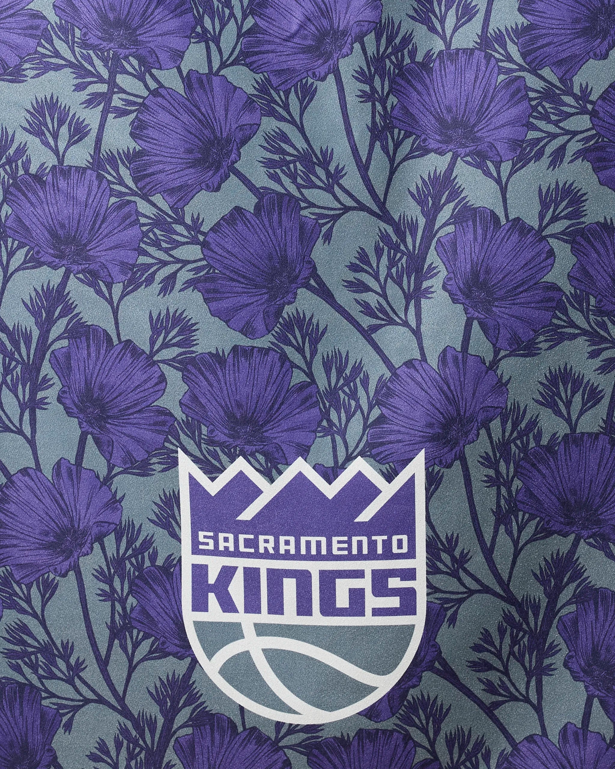 The Kings Floral beach towel by NBALAB x Geometry features the Sacramento Kings logo centered on illustrated purple flowers and green stems, made from quick-drying recycled materials.