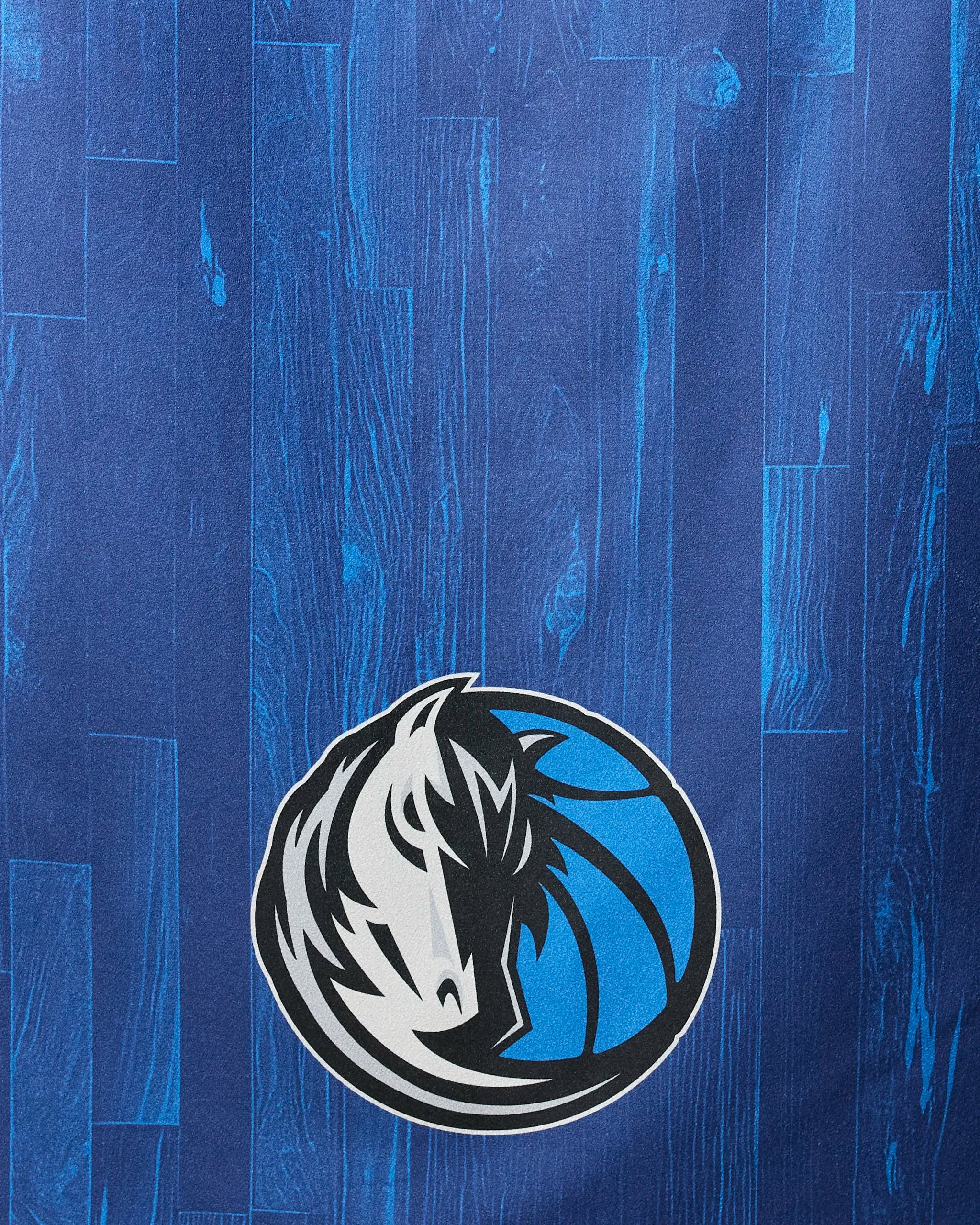 The image showcases Mavericks Zone by NBALAB x Geometry, displaying the Dallas Mavericks' horse logo in white, black, and blue on a blue wood-patterned background—ideal for an NBA beach towel.
