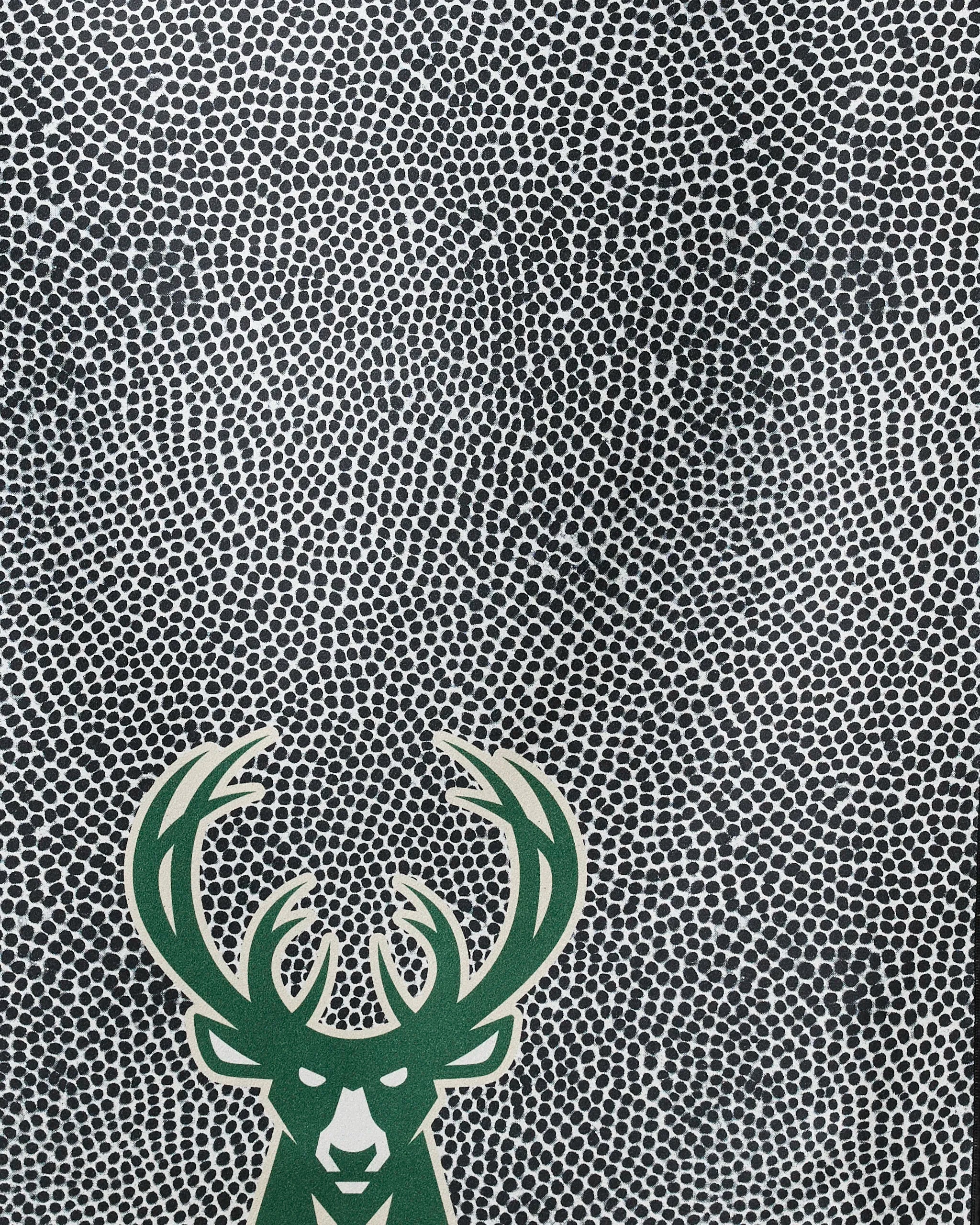 The Bucks Grip beach towel by NBALAB x Geometry features a stylized green deer head with large antlers in the lower left corner on a swirling black and white dotted background for standout style and quick-drying comfort.