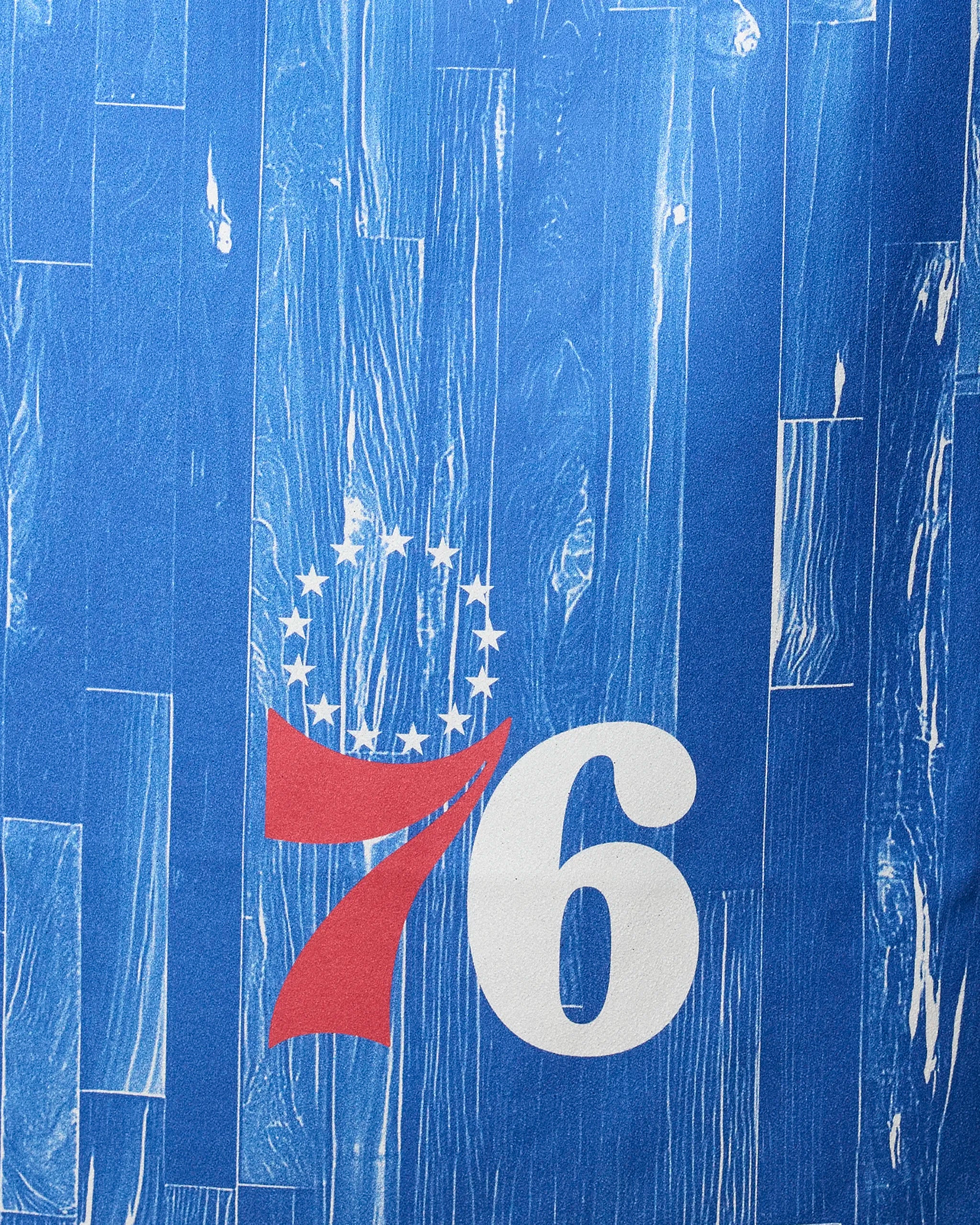 The image features the 76ers Zone logo by NBALAB x Geometry, with a red 7, white 6, and thirteen stars on a blue wood-textured background—ideal for an NBA beach towel crafted from ultra-absorbent recycled materials.