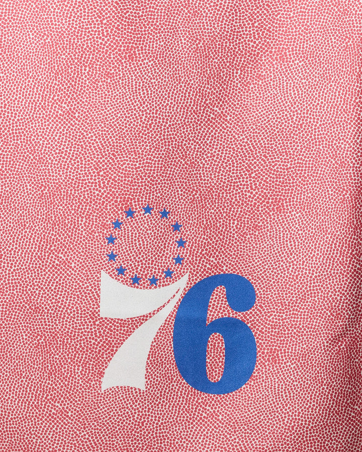 The NBALAB x Geometry 76ers Grip beach towel showcases a red textured background, bold white 7 and blue 6 forming "76," and thirteen blue stars above—an eye-catching, patriotic piece perfect for fans and summer outings.