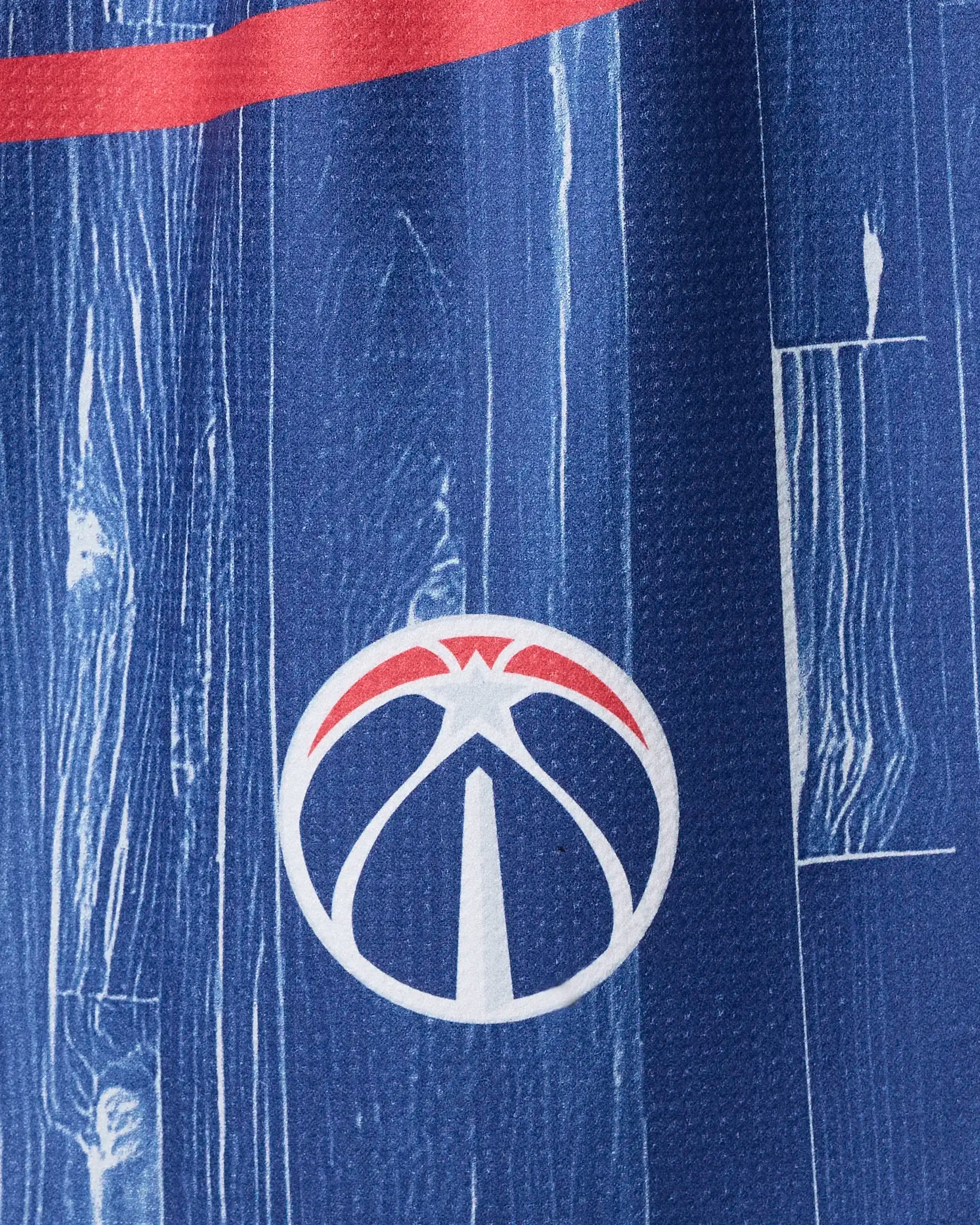 Close-up of the Wizards Zone towel by NBALAB x Geometry: blue fabric with a white basketball logo, red arc inspired by the Washington Wizards emblem, and wood-grain pattern with red and white lines—ideal stylish NBA tea towel for fans.