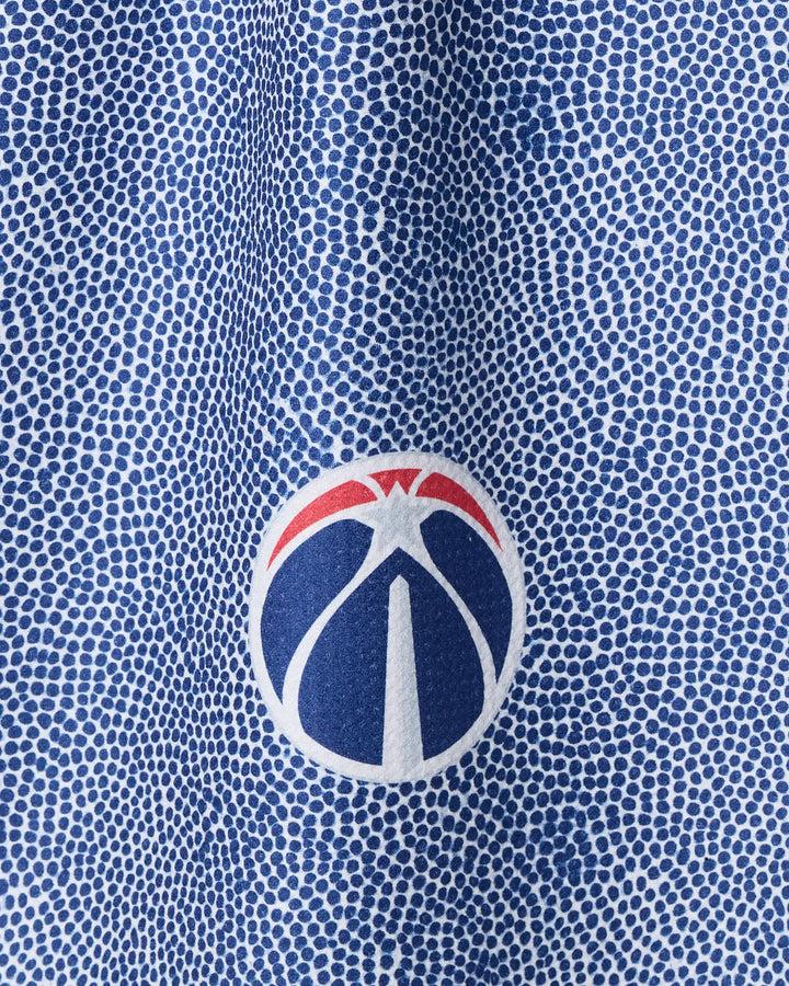 Close-up of a blue and white dotted fabric—this NBALAB x Geometry Wizards Grip tea towel features a circular logo with a stylized basketball in blue, white, and red at the center.
