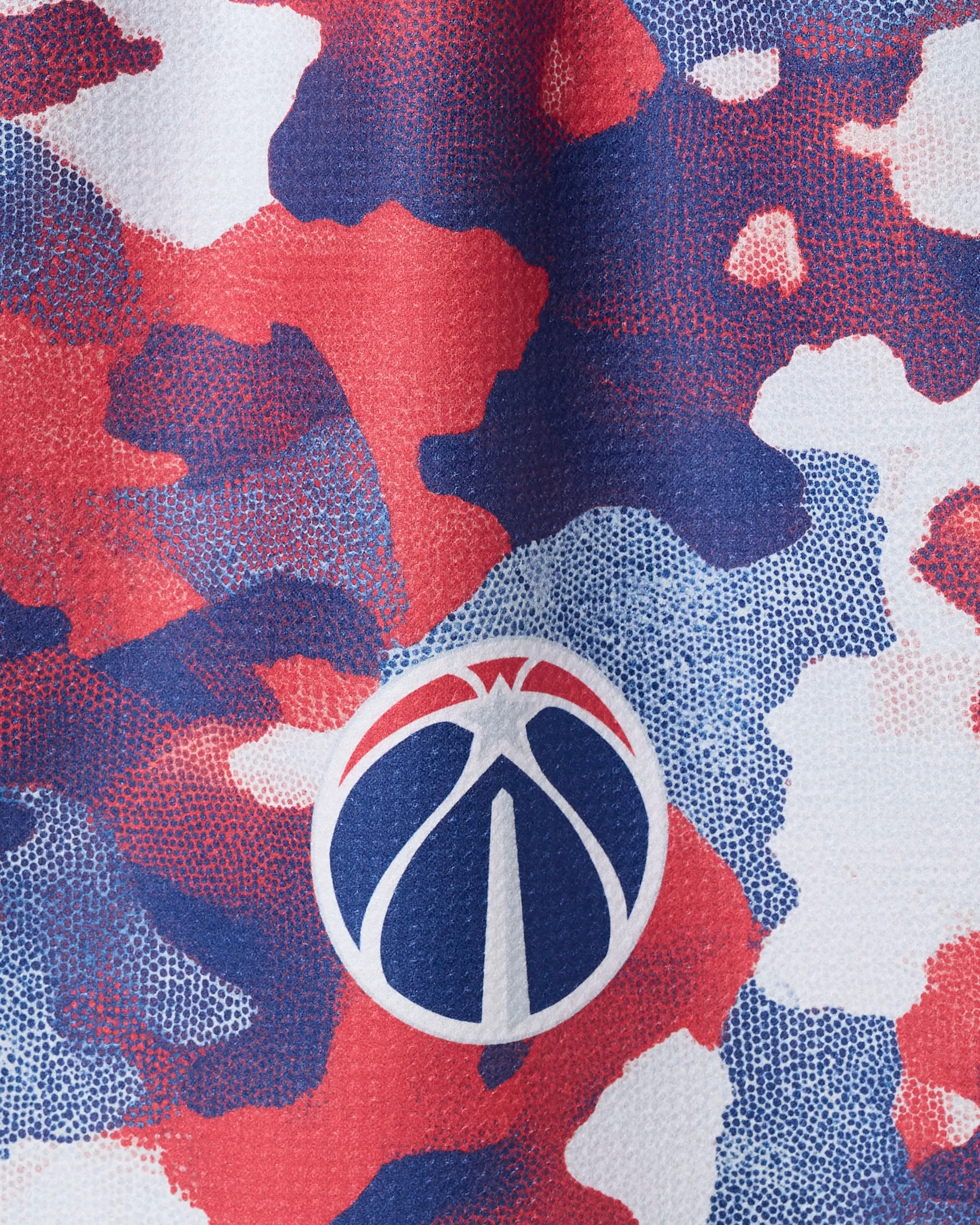 The Wizards Camo tea towel by NBALAB x Geometry features a red, white, and blue camouflage pattern with a white basketball logo and stylized Washington Monument, printed on sustainable material.
