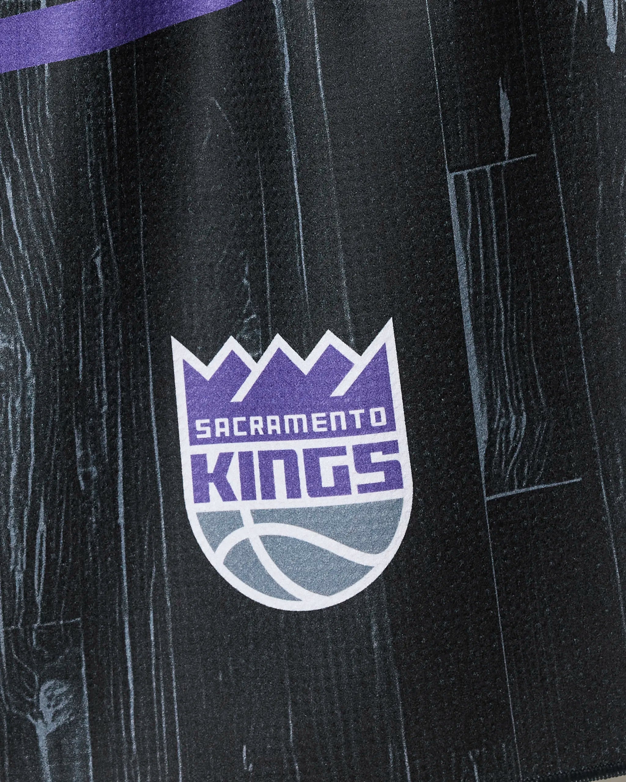The image shows the Sacramento Kings logo with a purple crown and grey basketball on a black wood-style background, similar to the "Kings Zone" tea towel by NBALAB x Geometry.