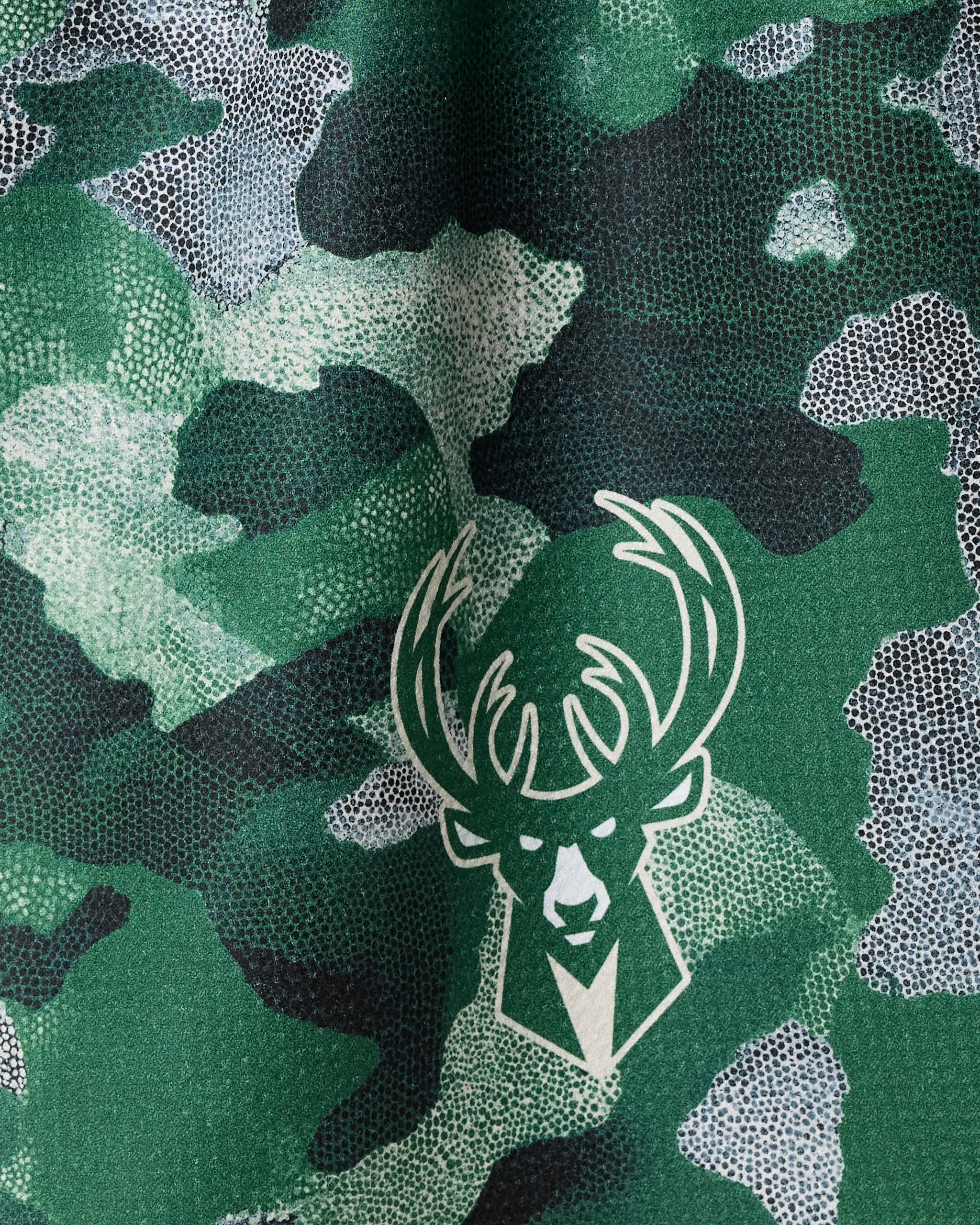 The Bucks Camo by NBALAB x Geometry features a green camouflage design with a white deer head logo—ideal as an NBA tea towel or sustainable kitchen towel for fans seeking distinctive style.