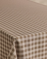 The Geometry Hazel Gingham tablecloth features a stain-resistant brown and white gingham pattern with evenly spaced diagonal checks, perfect for covering your rectangular table.