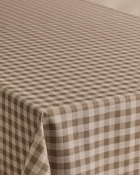 The Geometry Hazel Gingham tablecloth features a stain-resistant brown and white gingham pattern with evenly spaced diagonal checks, perfect for covering your rectangular table.
