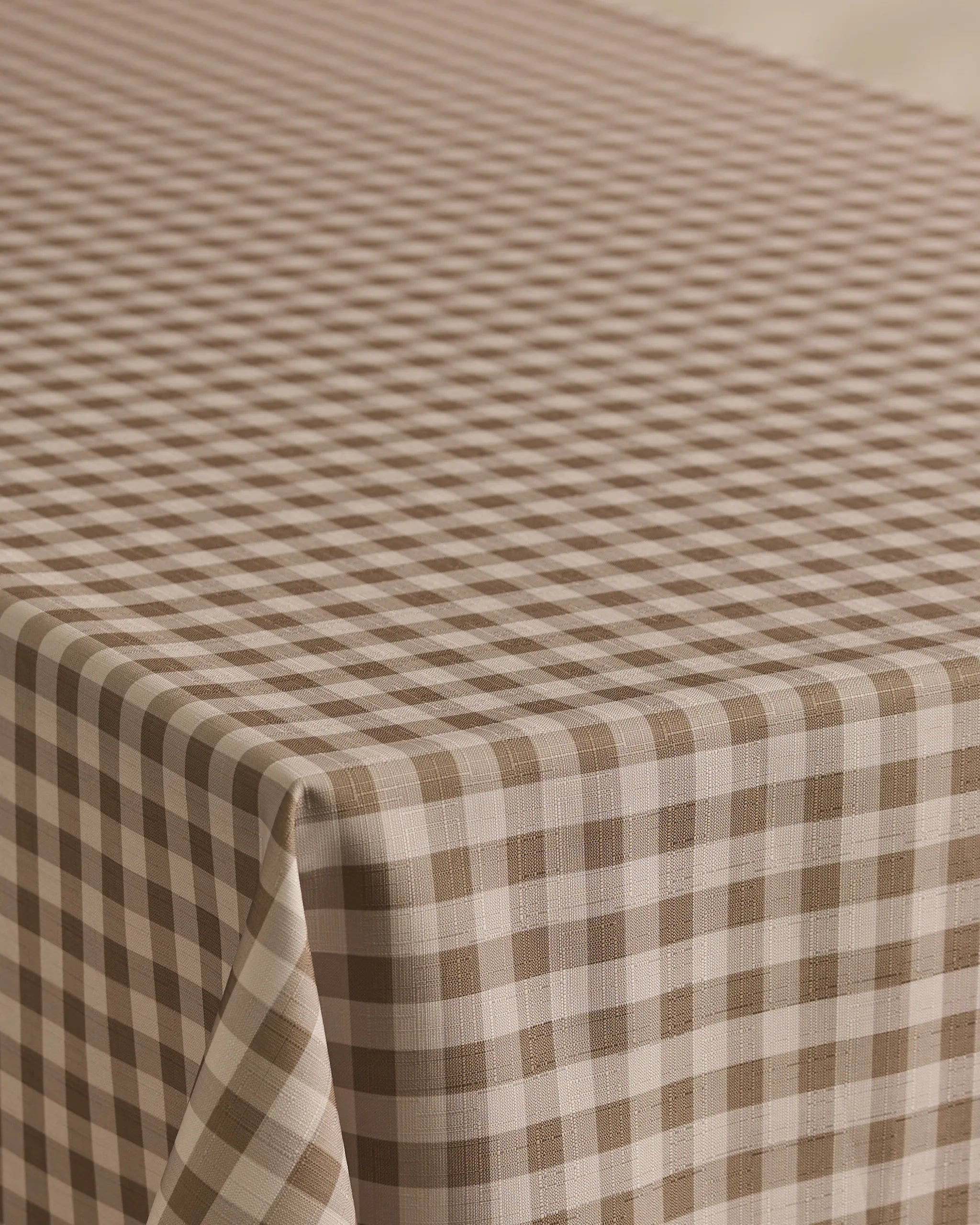 The Geometry Hazel Gingham tablecloth features a stain-resistant brown and white gingham pattern with evenly spaced diagonal checks, perfect for covering your rectangular table.