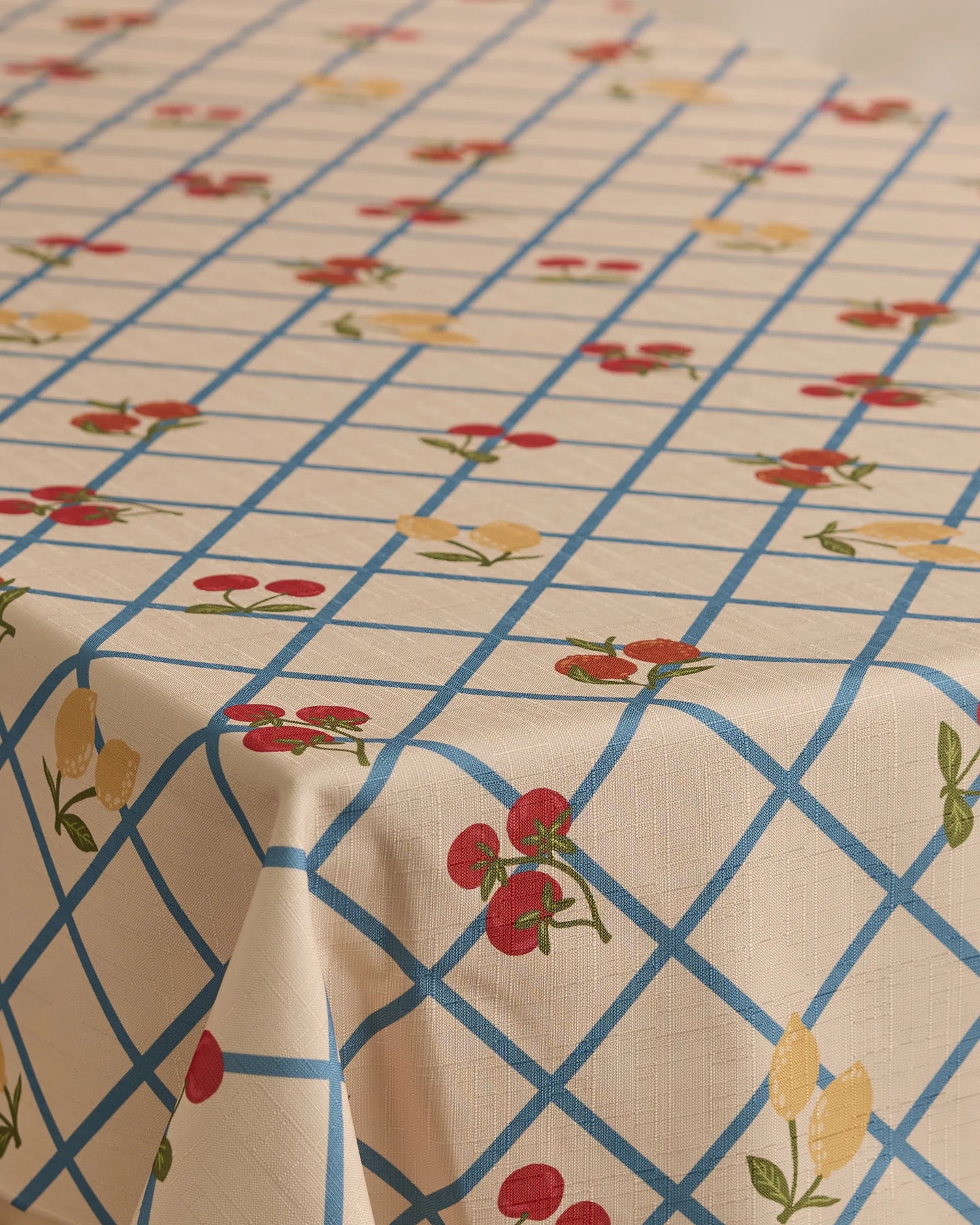 The Geometry Italian Summer Grid tablecloth, in beige with a blue grid and red cherries with yellow lemons print, offers a lightweight, stain-resistant cover for your rectangular table.