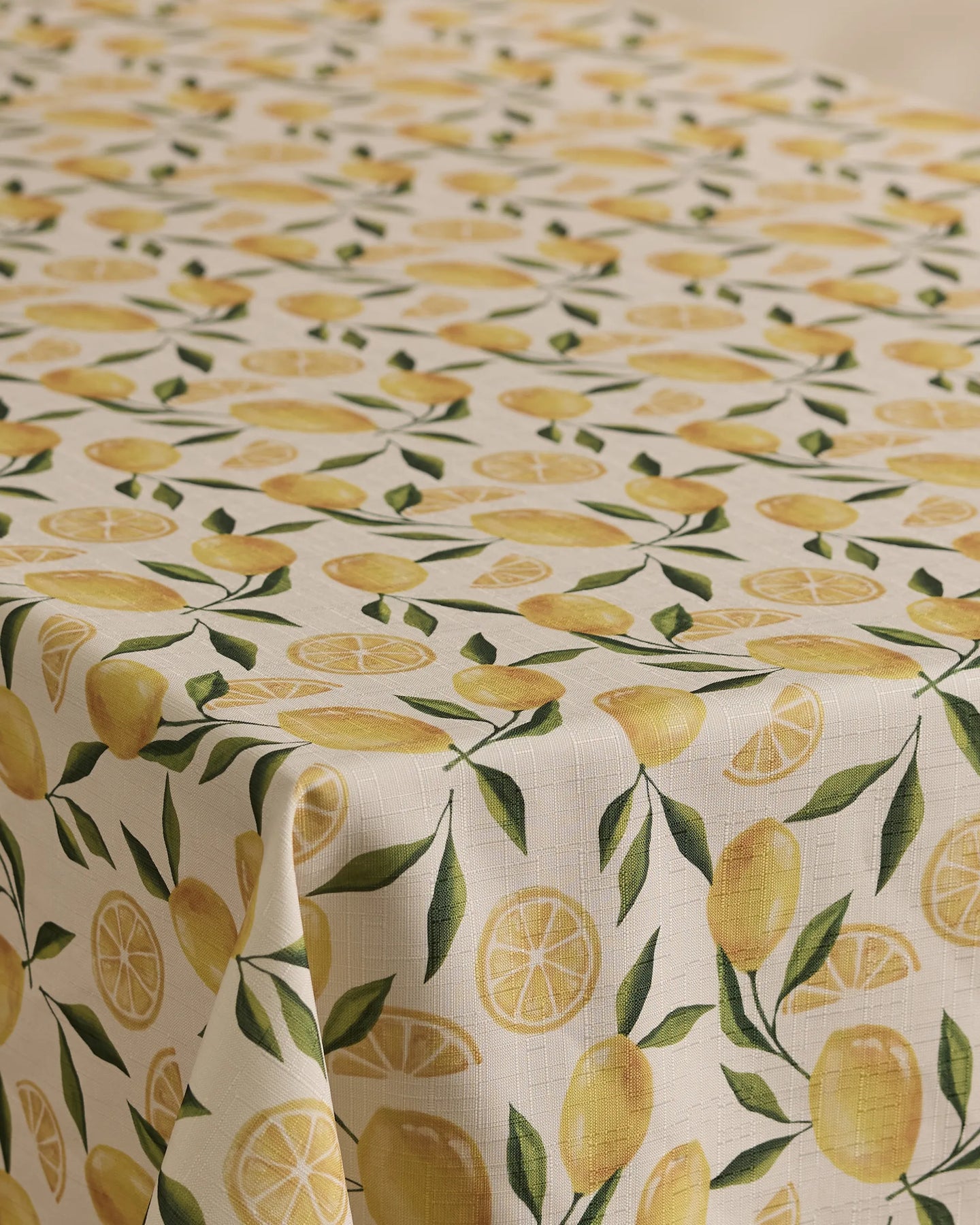 The Geometry Limoncello tablecloth has a cream background with a repeating pattern of whole lemons, lemon slices, and green leaves. Stain-resistant and stylish, its the perfect blend of function and flair for any dining space.
