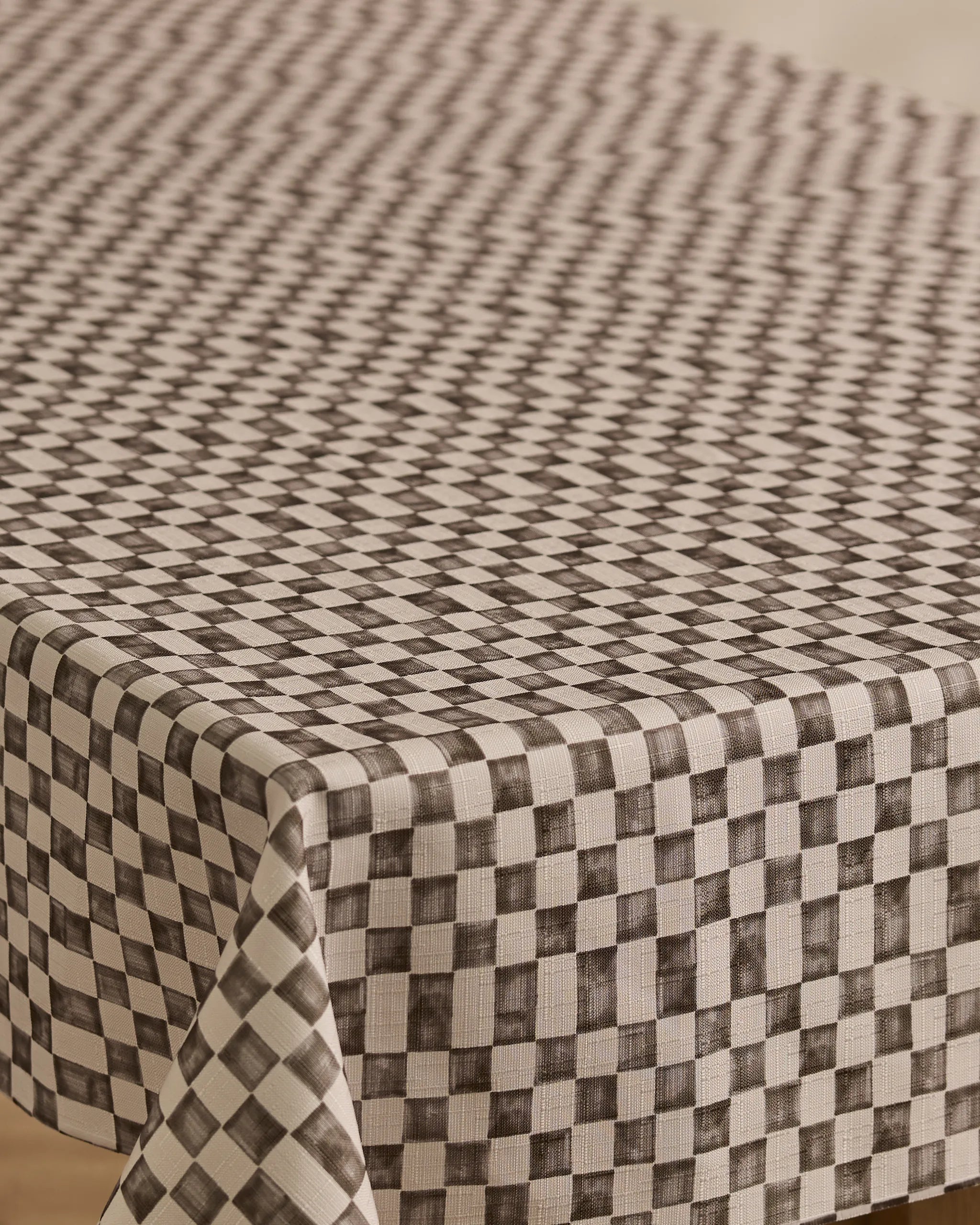 A close-up of Geometrys Tavern rectangular table covered with a stain-resistant, black and white checkered tablecloth featuring a geometric diamond pattern that creates an optical illusion effect.