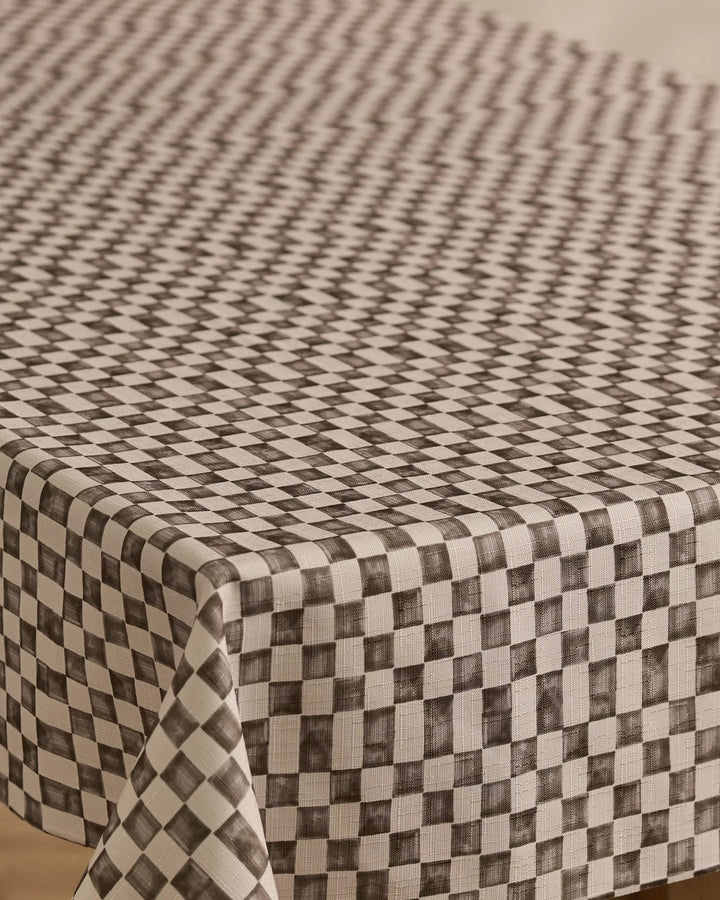 A close-up of Geometrys Tavern rectangular table covered with a stain-resistant, black and white checkered tablecloth featuring a geometric diamond pattern that creates an optical illusion effect.