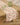 The Summer Air table runner by Geometry, featuring beige stain-resistant fabric with red food-themed illustrations, is laid on a wooden table set with green glassware in a softly lit room with wooden floors.