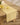 A light wood table features Geometry’s Sunny Sun yellow and white floral-patterned, stain-resistant table runner, topped with a bowl of lemons, a single lemon, and a white flower for a fresh, summery vibe.