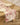 A wooden dining table features Geometrys Western Scene red and white patterned, stain-resistant table runner, neatly stacked cream-colored plates, a glass, and a small dried floral arrangement on top.