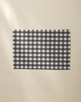 A Geometry Charcoal Gingham rectangular placemat is placed on a light beige textured surface.