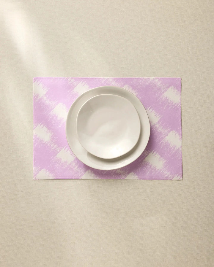 A white bowl and plate are stacked on the Geometry Hairy Check Pink recycled placemat, set on a light beige surface under soft lighting.