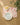A table setting featuring Geometry’s Summer Air placemats with red food-themed illustrations, a white plate, pale blue bowl, and apple slices in a small dish sits beside a leafy green plant. All placemats are machine washable.