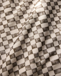 A close-up of Geometry’s Tavern tablecloth reveals a black and white checkered pattern with shaded squares; the stain-resistant fabric has visible folds and a soft, textured surface.