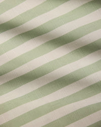 Close-up of Seagrass fabric by Geometry, featuring pale green and white horizontal stripes. Its subtle grid pattern and gentle folds make it ideal for a stain-resistant, recycled-material table runner.