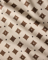 The Heritage Stamp tablecloth by Geometry features beige fabric with a repeating dark brown geometric pattern and dots, accented by subtle diagonal shadows—an eco-friendly choice perfect for modern homes.