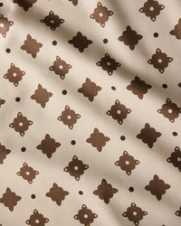 The Heritage Stamp tablecloth by Geometry features beige fabric with a repeating dark brown geometric pattern and dots, accented by subtle diagonal shadows—an eco-friendly choice perfect for modern homes.