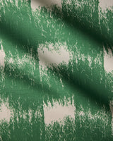 A close-up of Geometry’s Hairy Check Green table runner fabric shows its green and white rough brushstroke checkered pattern, highlighting the slight creases and texture.