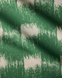 The Hairy Check Green tablecloth by Geometry features a green and white checkered pattern with textured, painted effects, rough-edged green stripes, visible fabric weave, and light creases for a unique look.