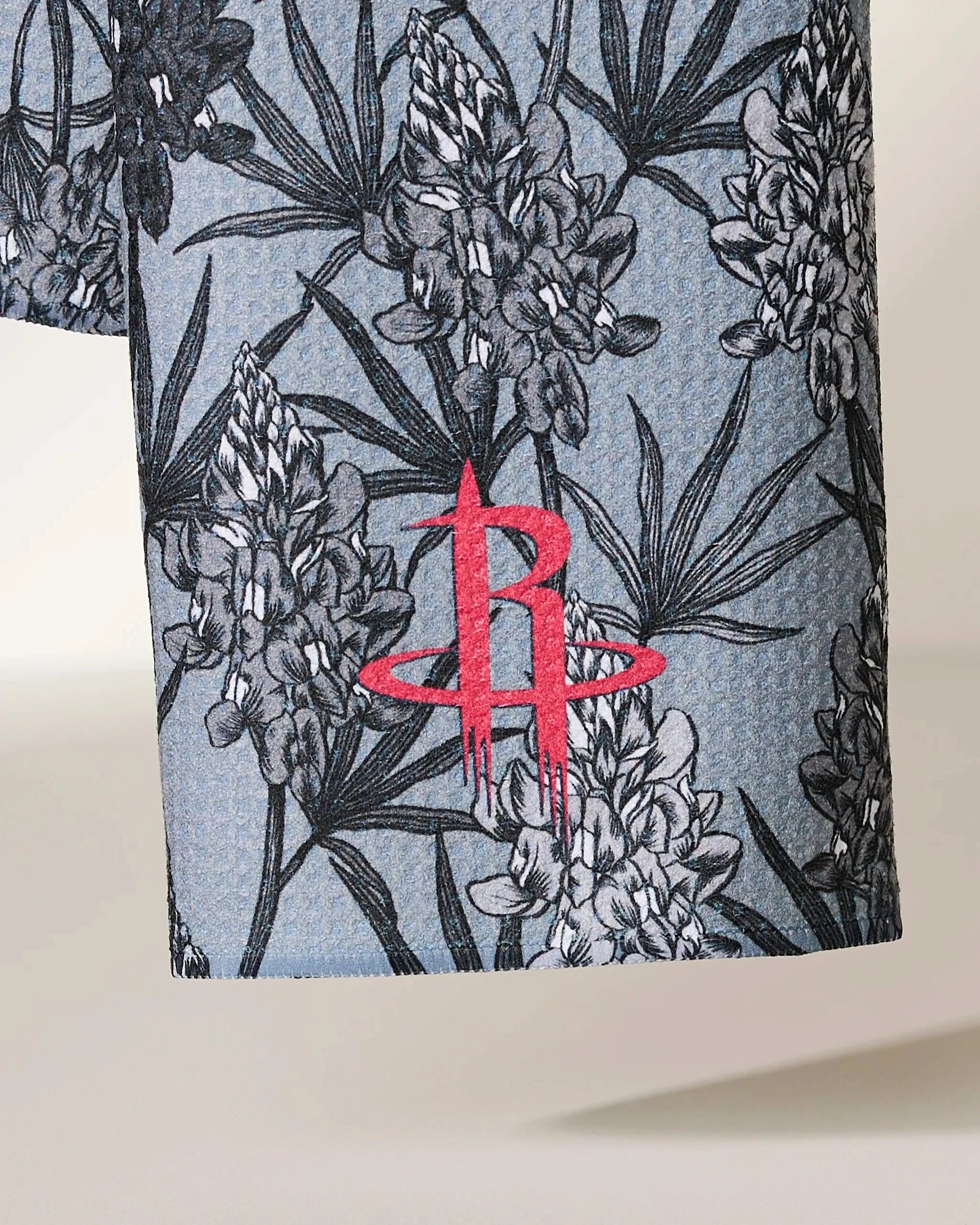 Close-up of Geometrys Rockets Floral fabric, showcasing a black and white floral pattern on blue with the red Houston Rockets logo embroidered.