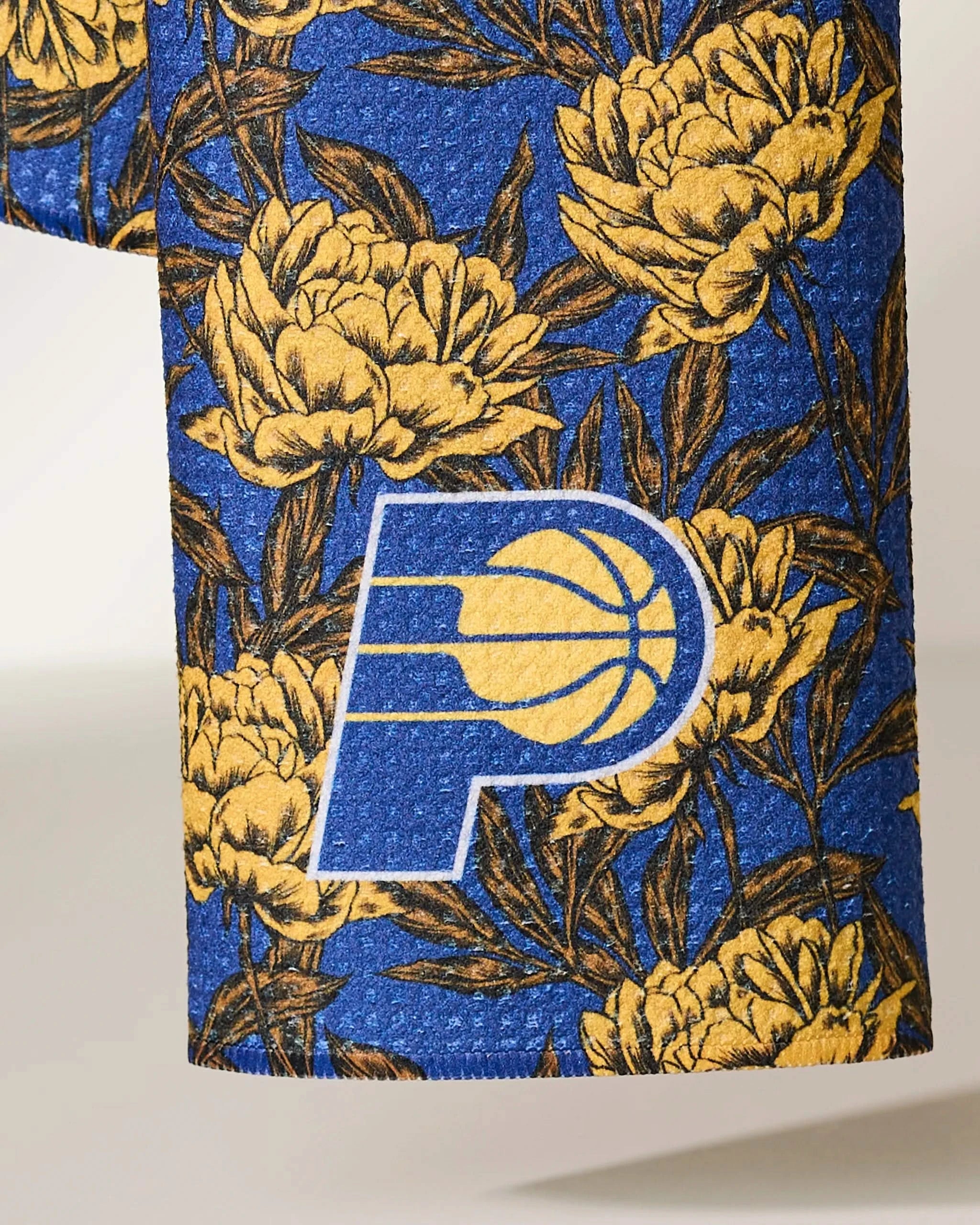 A close-up of the Geometry Pacers Floral fabric, featuring a blue background with a yellow floral pattern and the Indiana Pacers basketball logo prominently displayed.