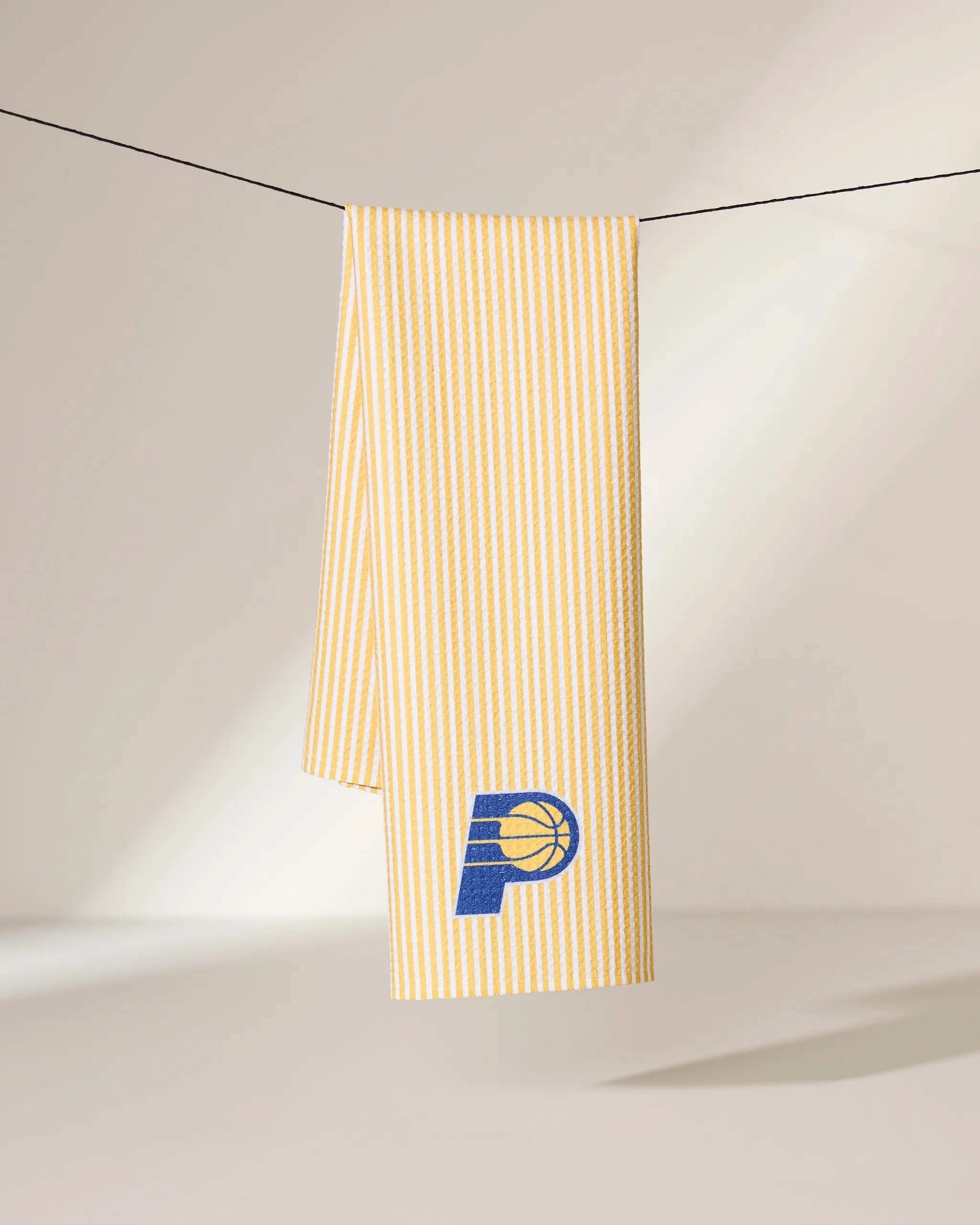 The Pacers Classic by Geometry—a yellow and white striped scarf featuring the blue and yellow Indiana Pacers basketball logo—hangs on a black string against a neutral background.