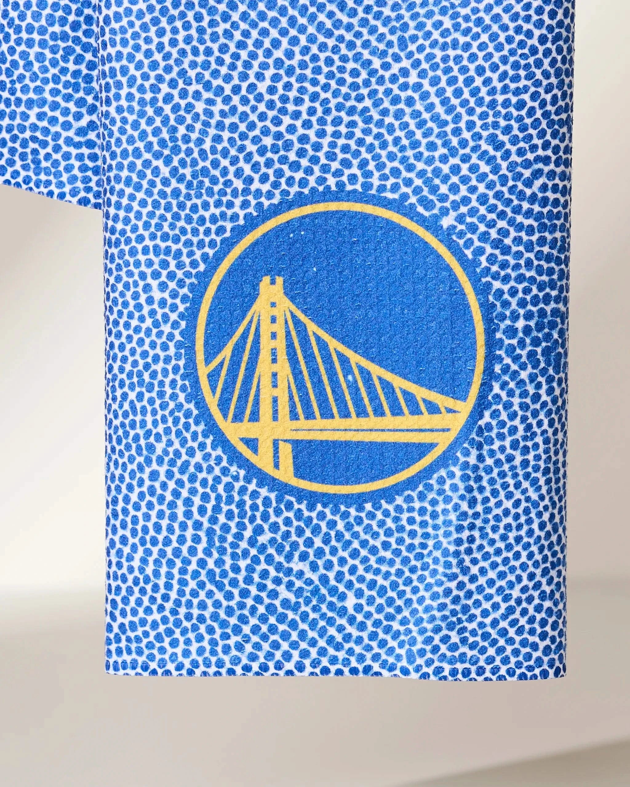 The Warriors Grip by Geometry is a blue cloth with small white dots and a yellow outline of the Golden Gate Bridge in a blue circle.