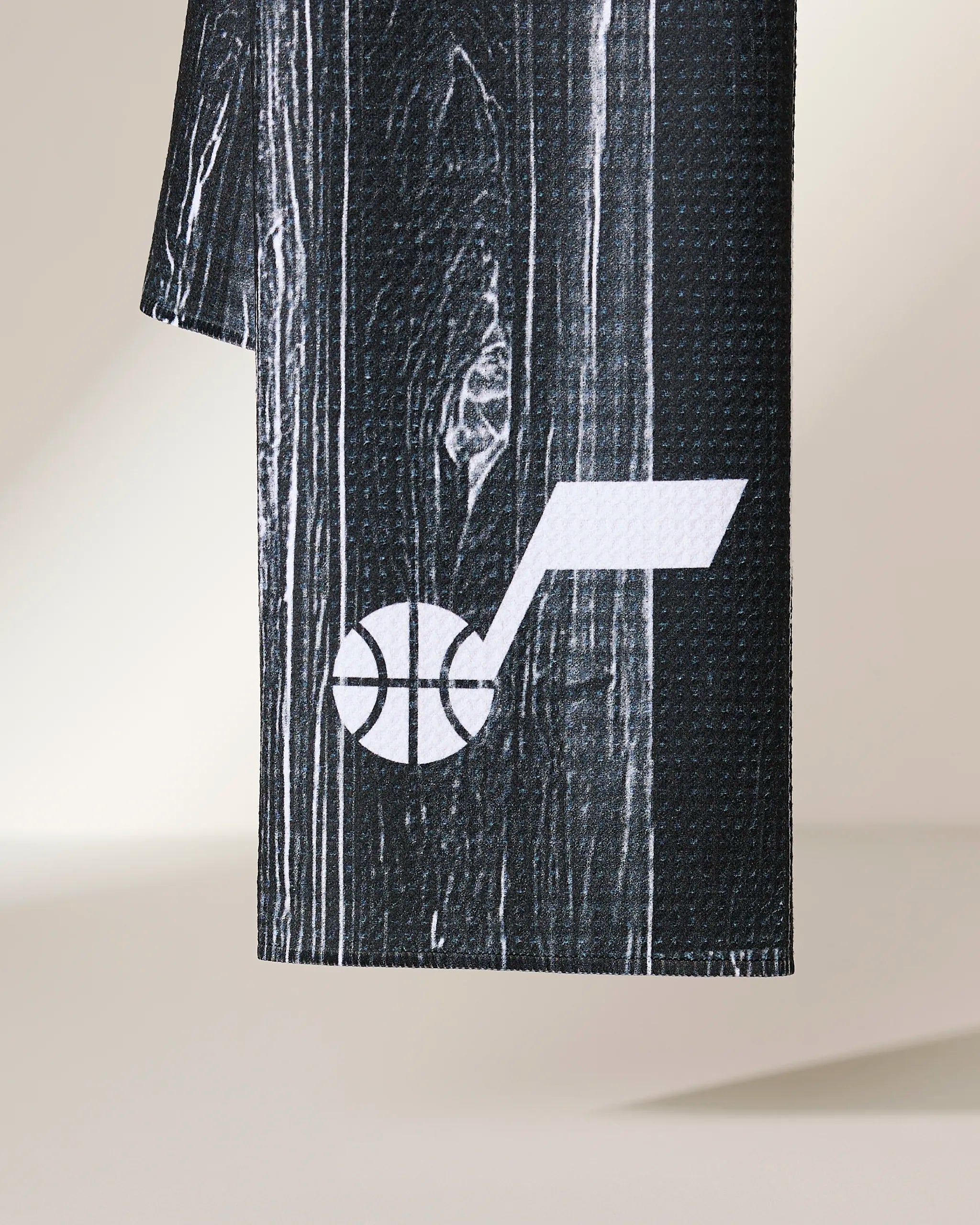 A close-up of the black textured fabric on the Geometry Jazz Zone, featuring a white Utah Jazz logo with a stylized musical note and basketball.