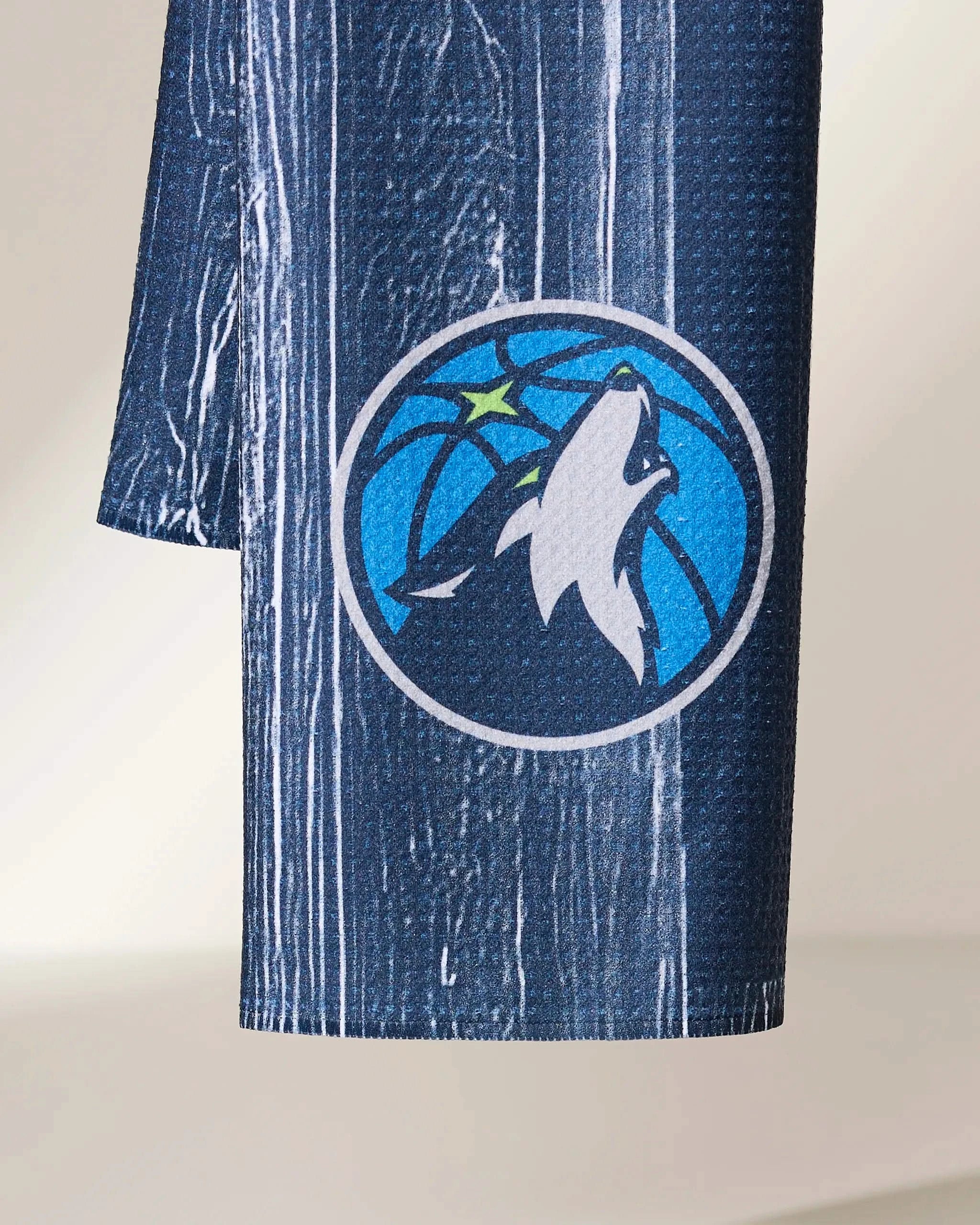 A close-up of the Timberwolves Zone by Geometry shows dark blue textured fabric with the Minnesota Timberwolves logo—a howling wolf in front of a blue basketball and green stars.