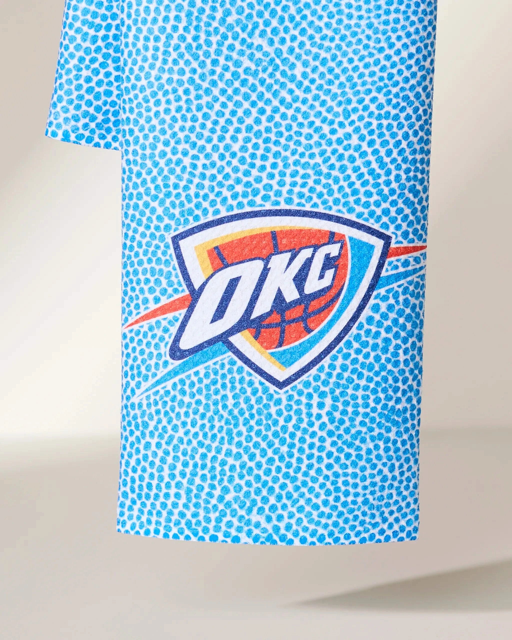 The Geometry OKC Grip towel is blue with a dotted pattern and showcases the Oklahoma City Thunder team logo at the center.