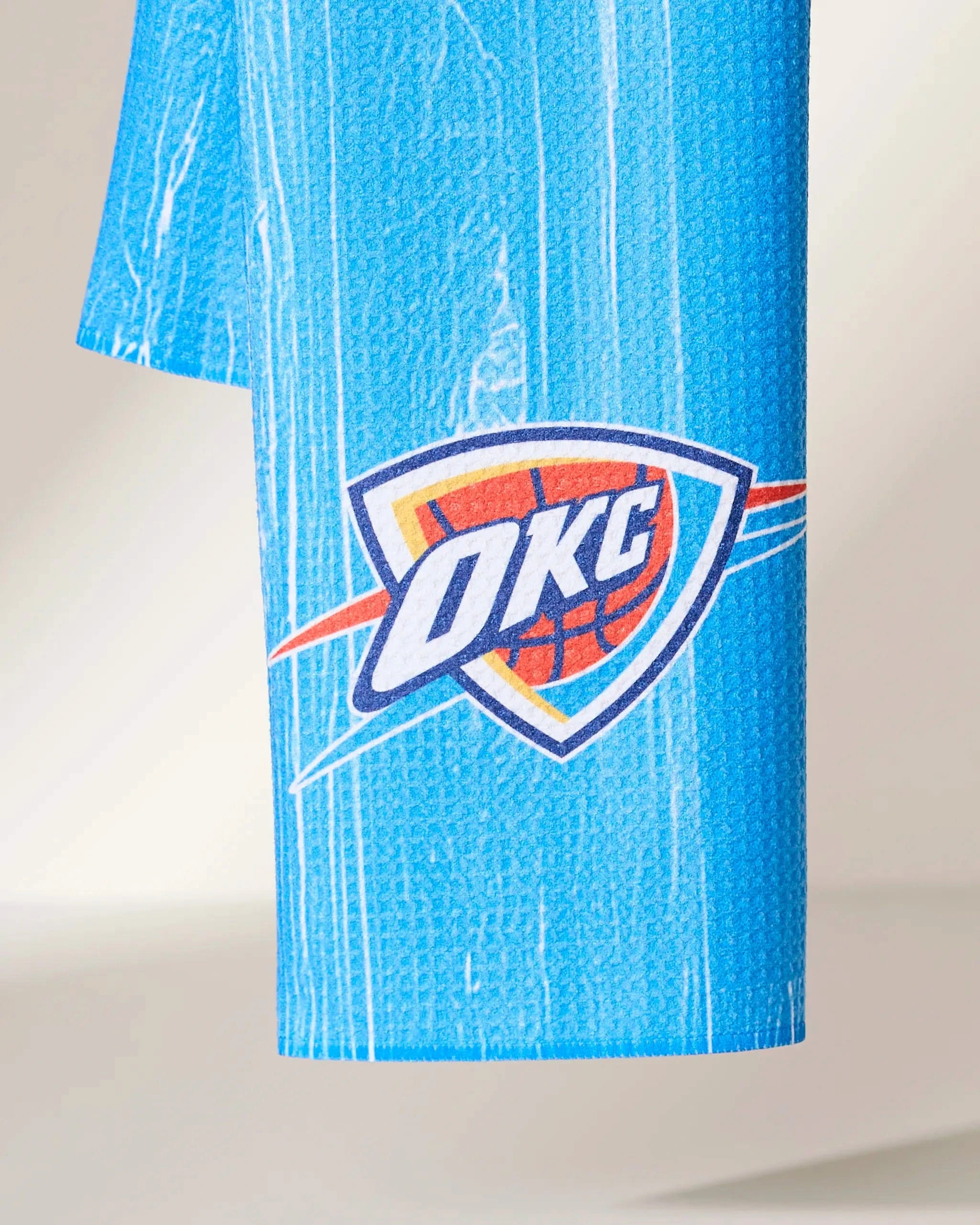 A close-up of the OKC Zone by Geometry shows blue textured fabric with the Oklahoma City Thunder logo—OKC over a basketball with orange, white, and blue accents.