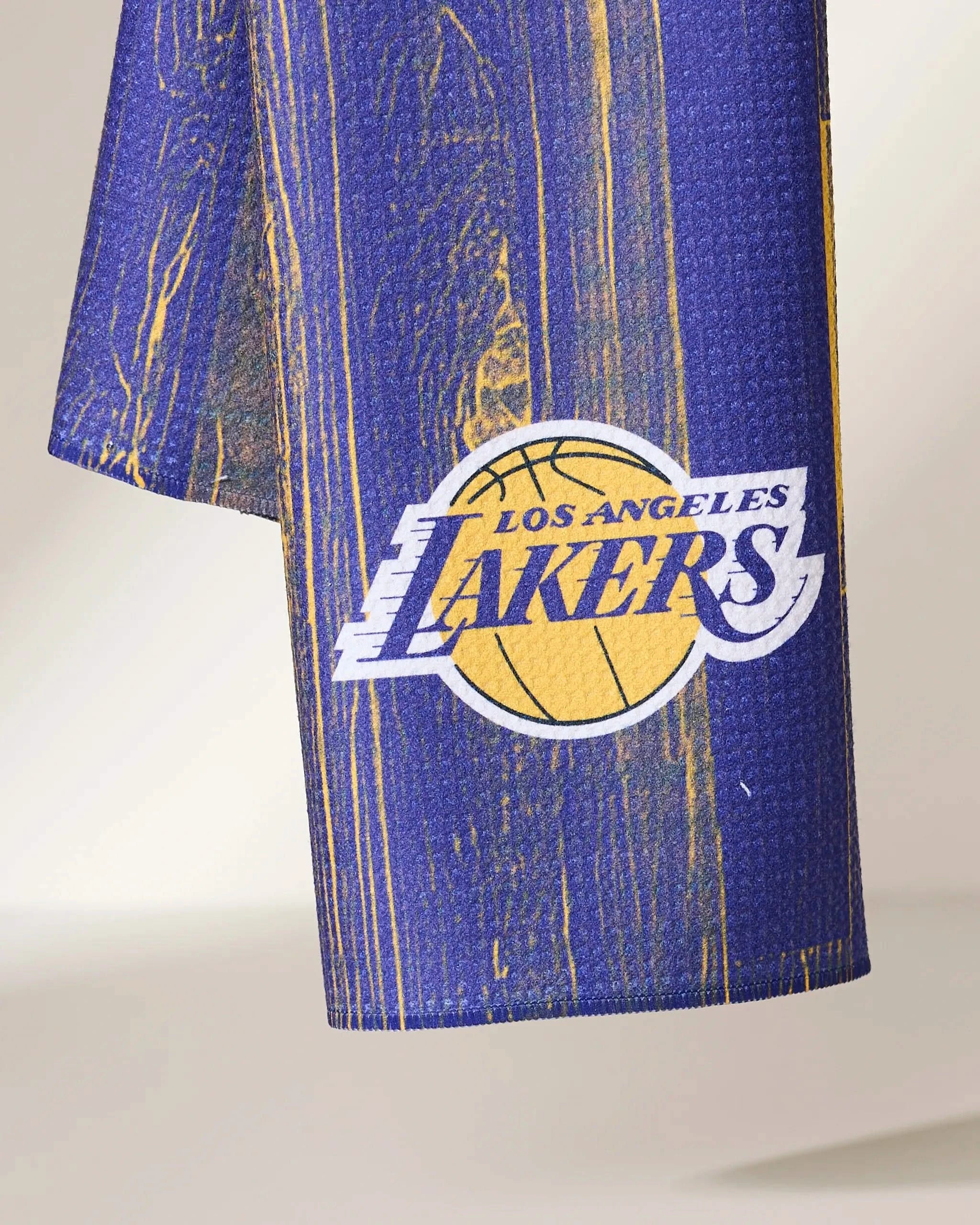 A close-up of Lakers Zone by Geometry shows blue and gold textured fabric with the Los Angeles Lakers logo, basketball graphic, and bold text on a neutral background.